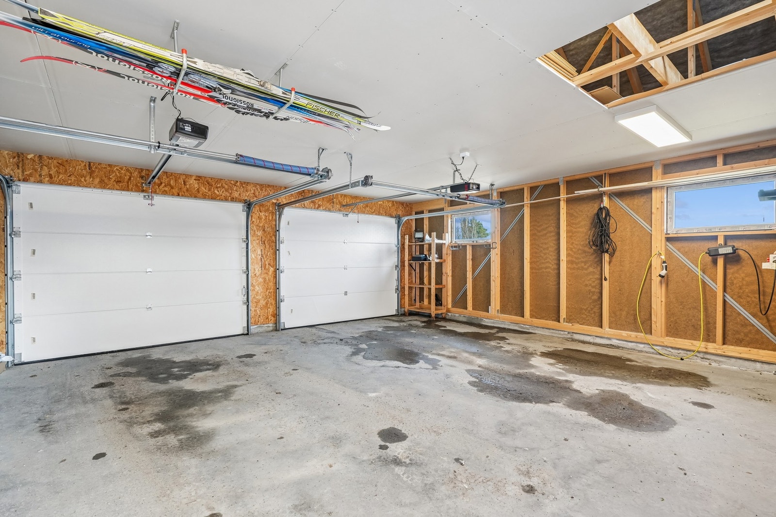 Garasjen har elektriske ledporter og ytterdør. Det er innvendig belysning, stikkontakter, elbillader, sikringsskap og lysbryter. Himling/etasjeskille er kledd med gipsplater. God oppbevaringsplass. Galleribilde