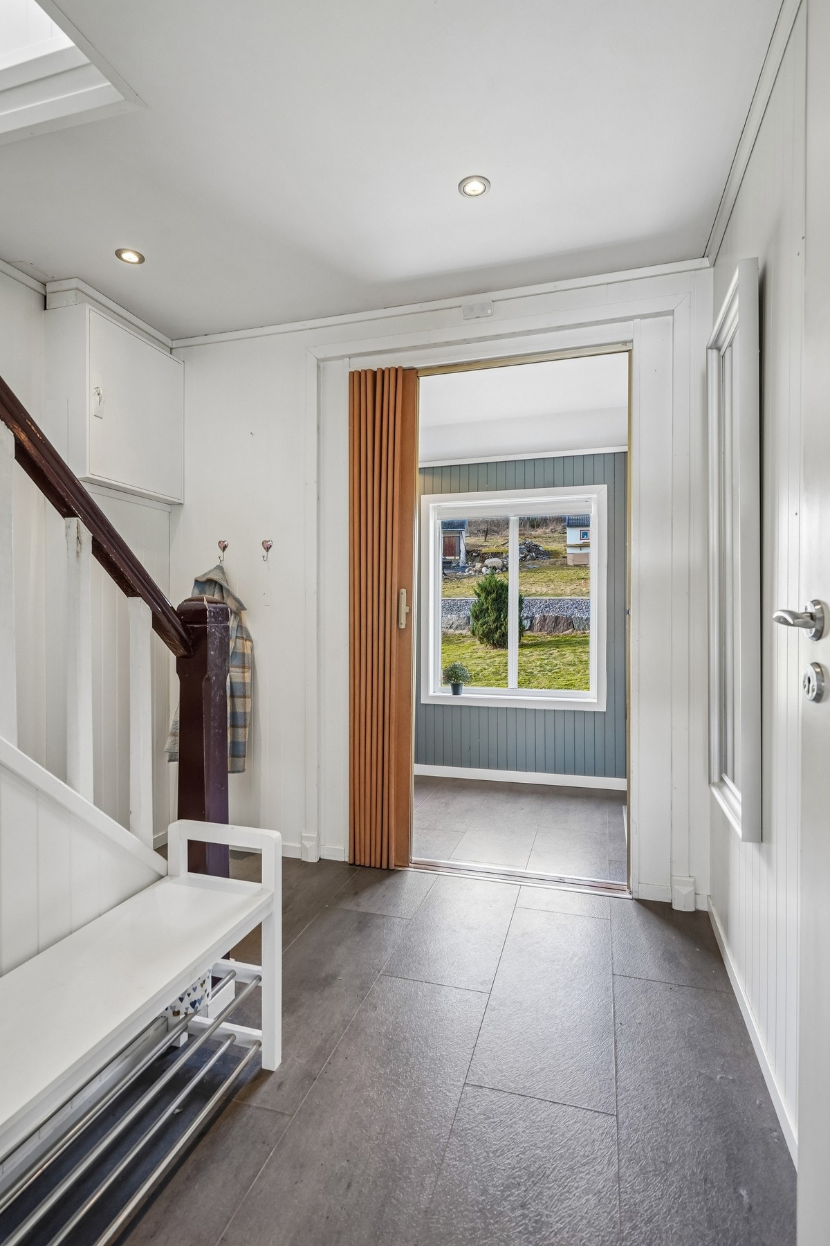 Det er foldedør mellom gang og entré. Gulvoverflater av laminat og på veggene er det malt panel. Slett himling med ledspotter. Galleribilde