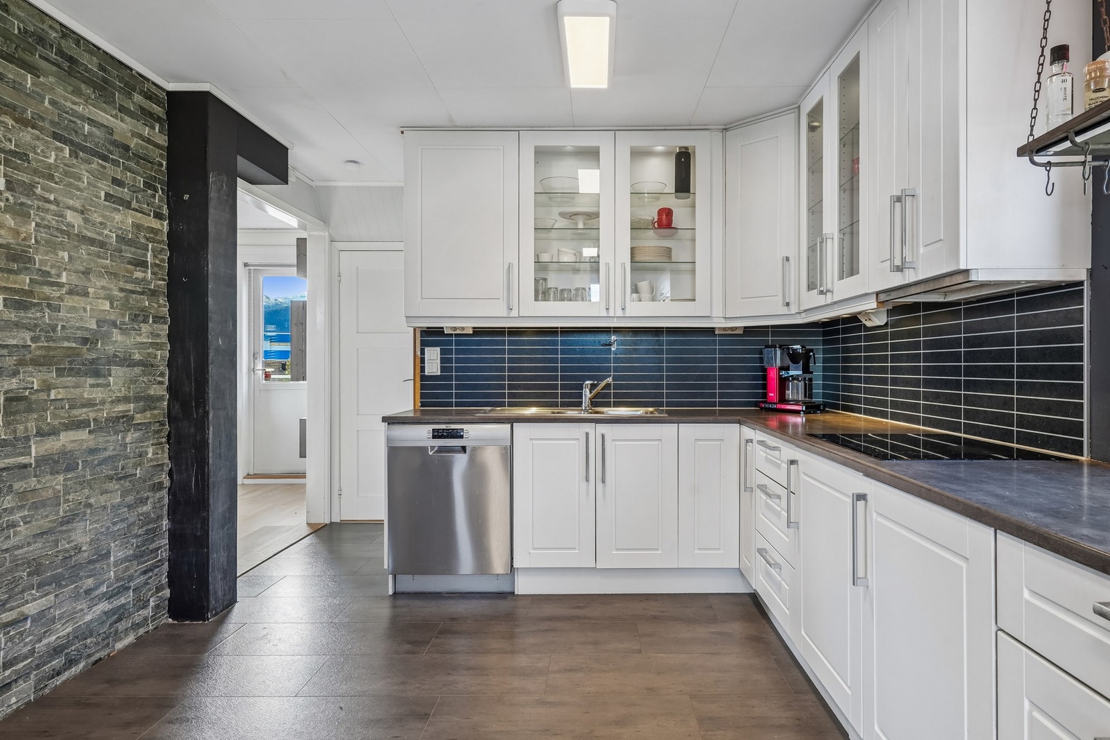 Det er montert vannbestandige plater på veggen under overskap med belysning. Galleribilde