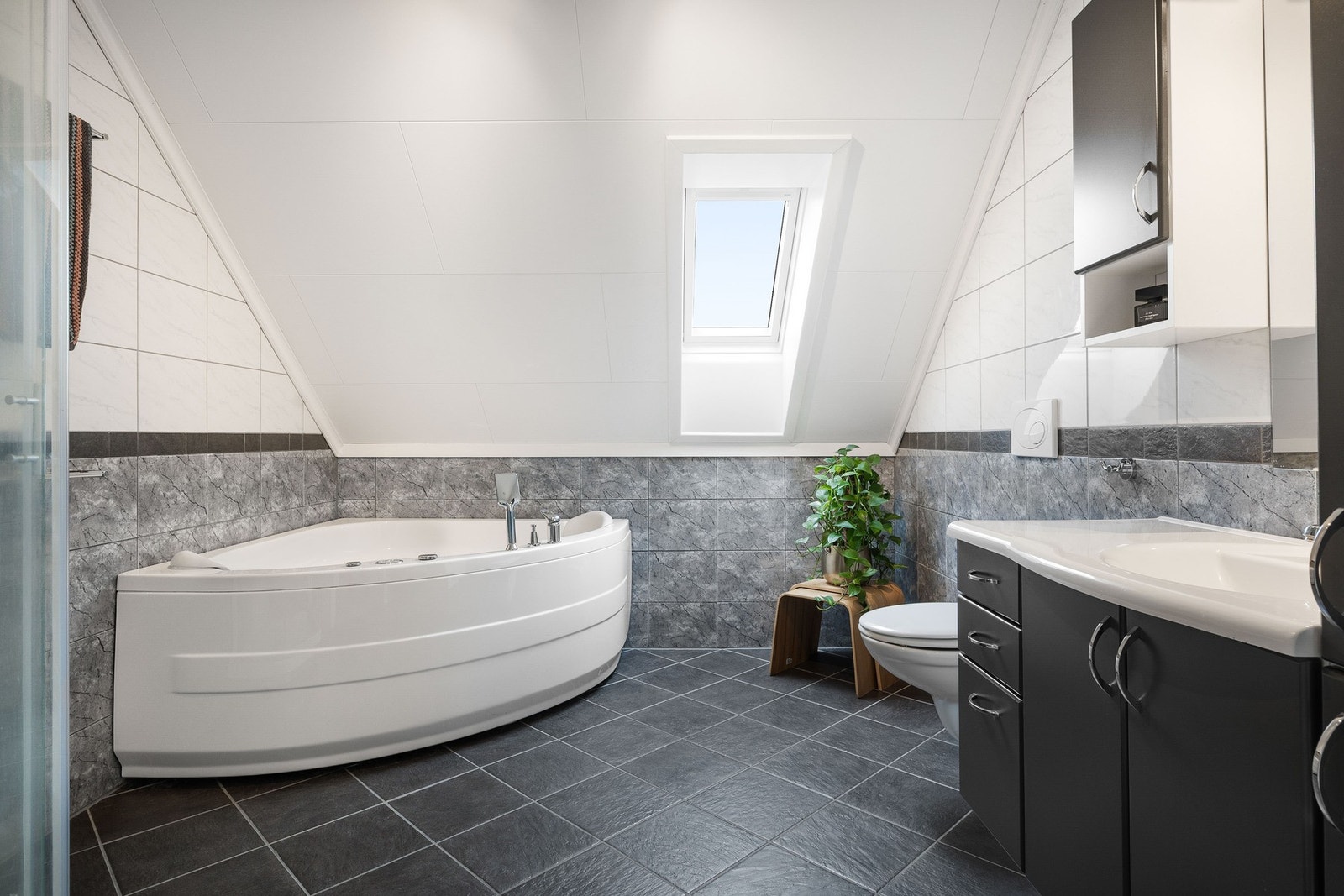 Stort, flislagt bad med dusjkabinett, badekar, servant i innredning, vegghengt toalett i et delikat fargevalg. Galleribilde