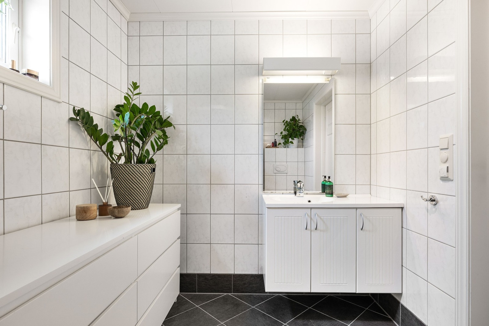 Lyst og delikat, flislagt bad med servant i innredning , dusjkabinett og vegghengt toalett. Galleribilde