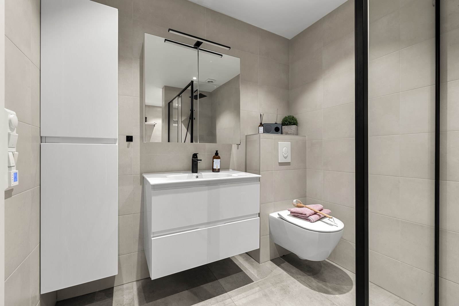 Badet er utstyrt med vegghengt toalett, servant med skuffer og dusjnisje med glassvegg. Galleribilde