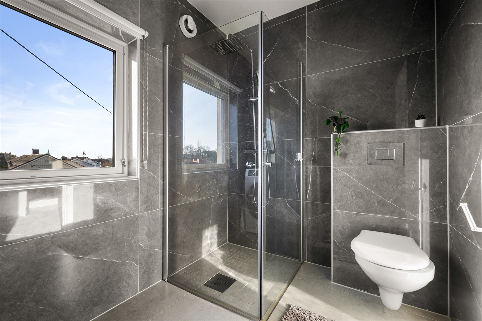 Badet er utstyrt med flott dusjhjørne, vegghengt toalett og servant innredning. Galleribilde