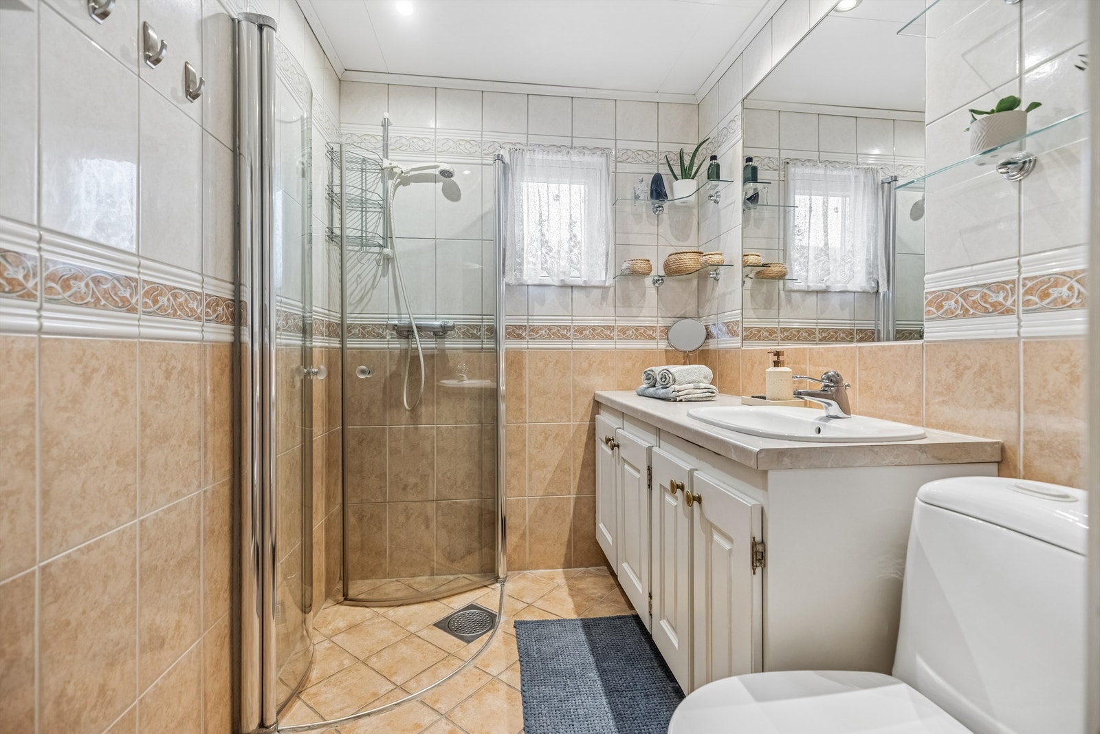 Flislagt bad med gulvvarme. Stor servantinnredning med god plass til oppbevaring. Dusjhjørne med innadslående glassdører samt gulvstående toalett. Galleribilde