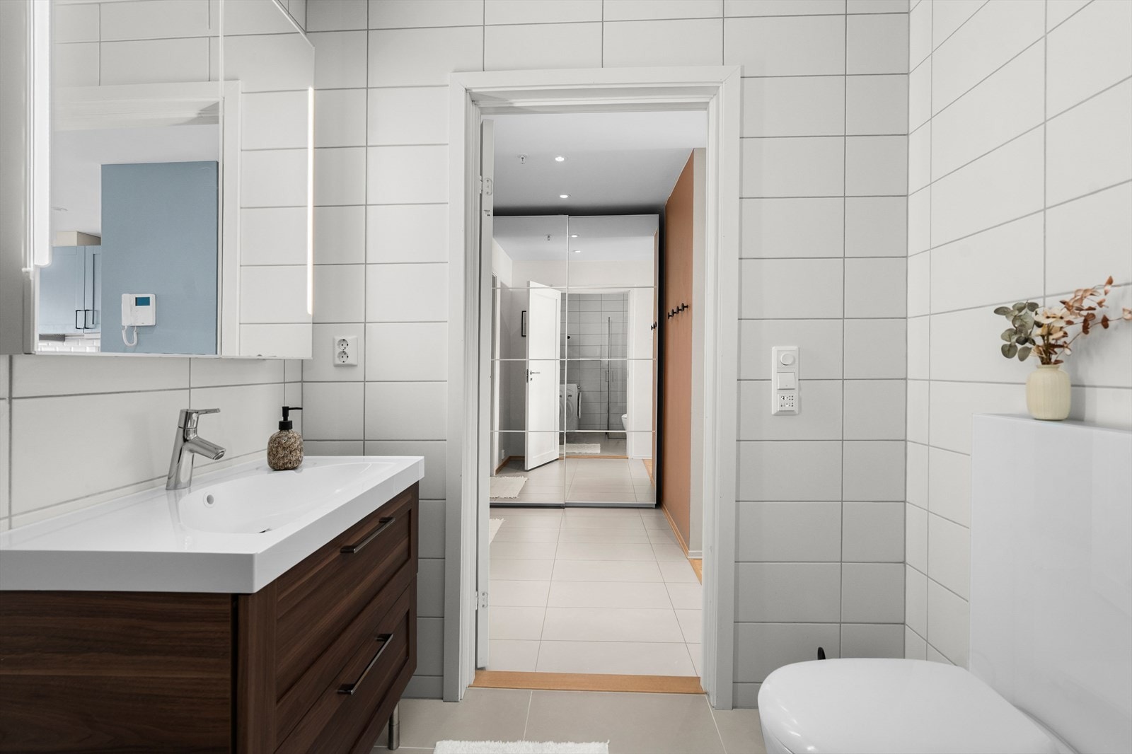 Badet er utstyrt med innfellbare dusjdører, baderomsinnredning, vegghengt klosett og opplegg for vaskemaskin. Galleribilde