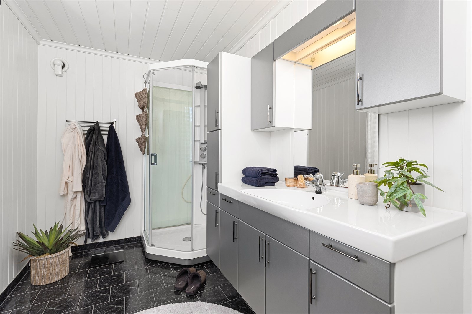 Badet er av god størrelse hvor det er fliser på gulvet med varmekabler, samt panel på veggene og i himlingen. Det inneholder et praktisk dusjkabinett, en stor baderomsinnredning samt toalett. Galleribilde