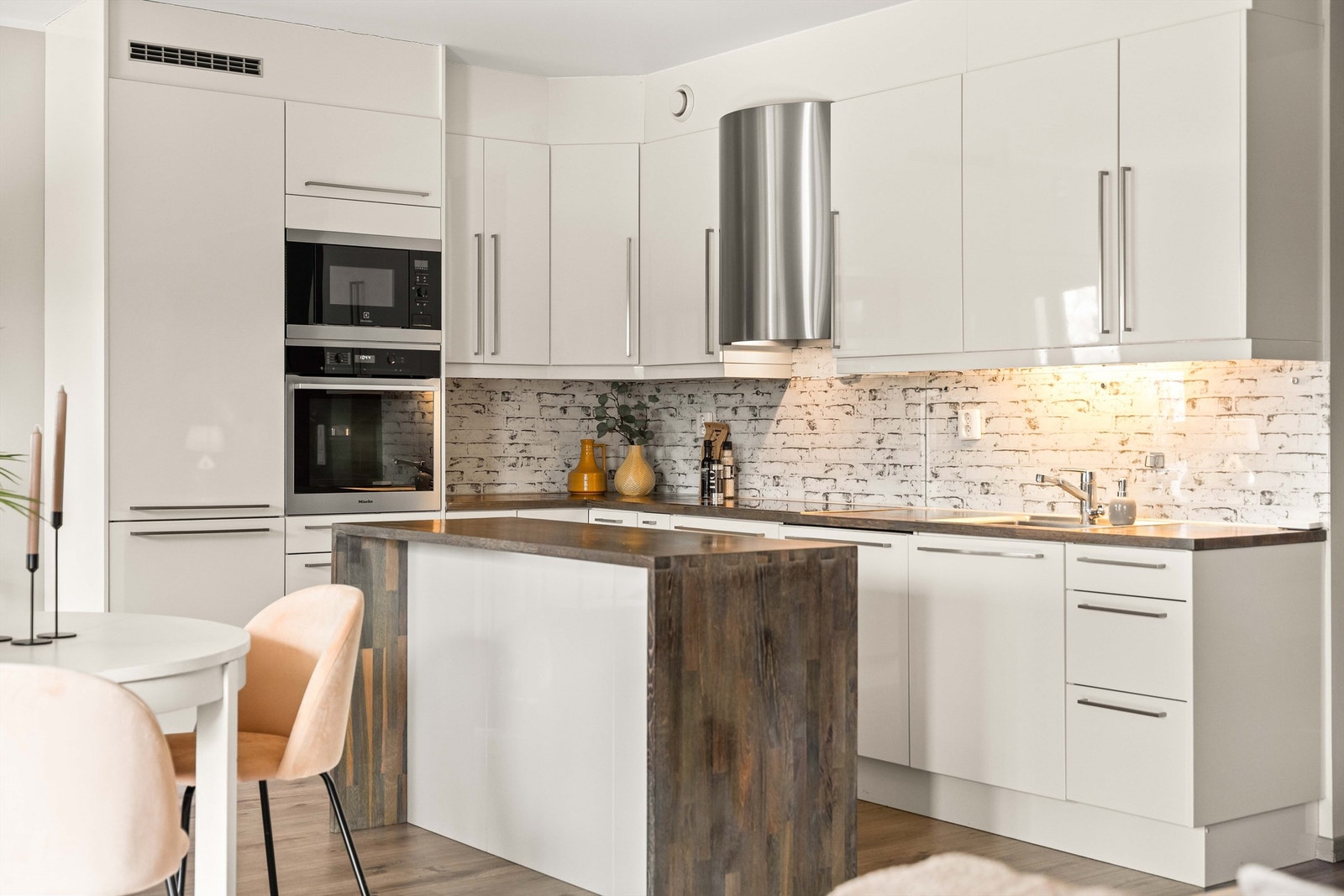 Moderne og funksjonell kjøkkeninnredning med integrerte hvitevarer og praktisk kjøkkenøy. Slette fronter kombinert med treverk gir et tidløst uttrykk. God belysning og smarte løsninger sikrer en behagelig arbeidssone. Galleribilde