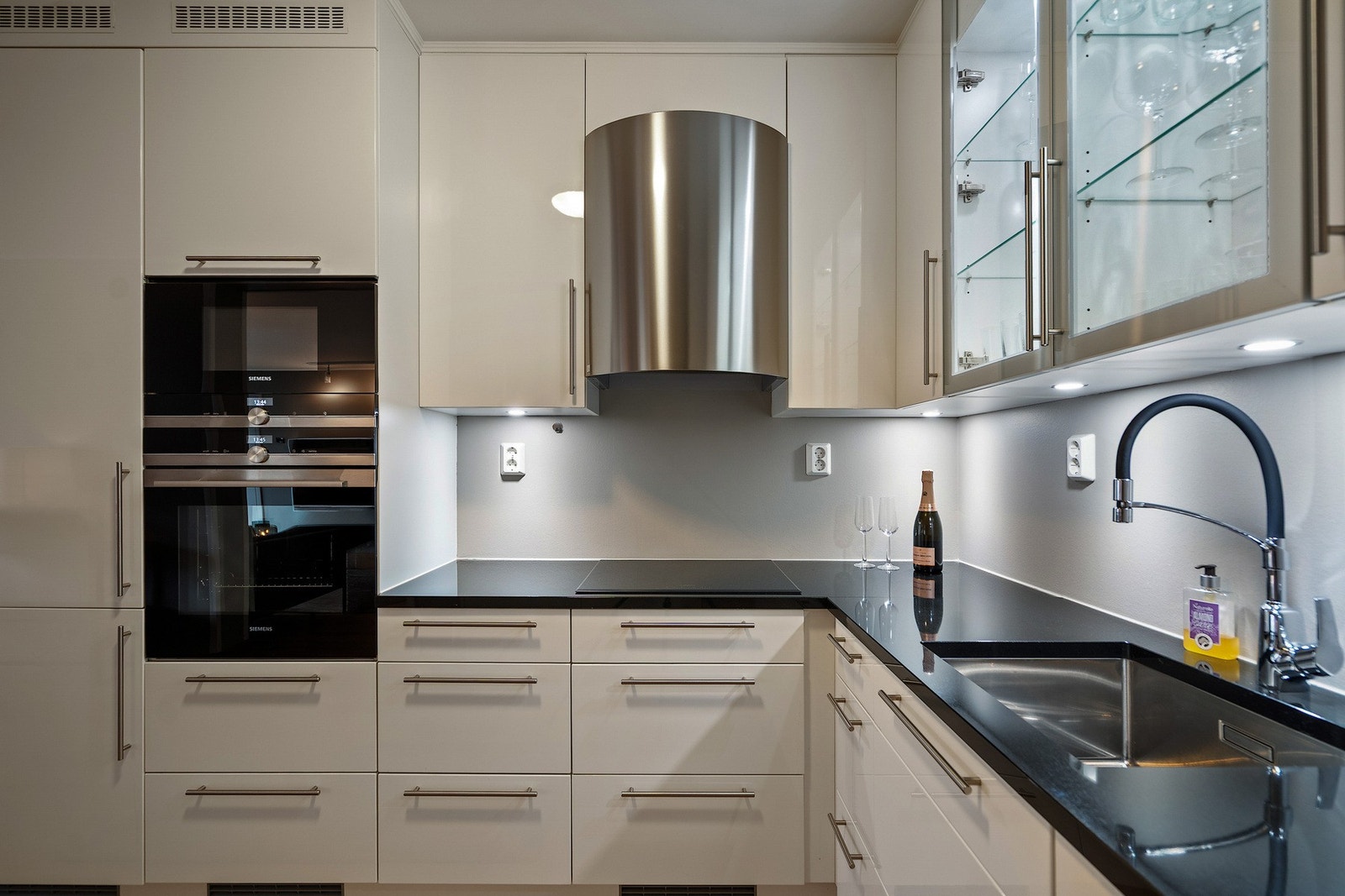 Hvitevarer som stekeovn, induksjonstopp, kjøleskap og oppvaskmaskin er integrert i kjøkkeninnredningen Galleribilde