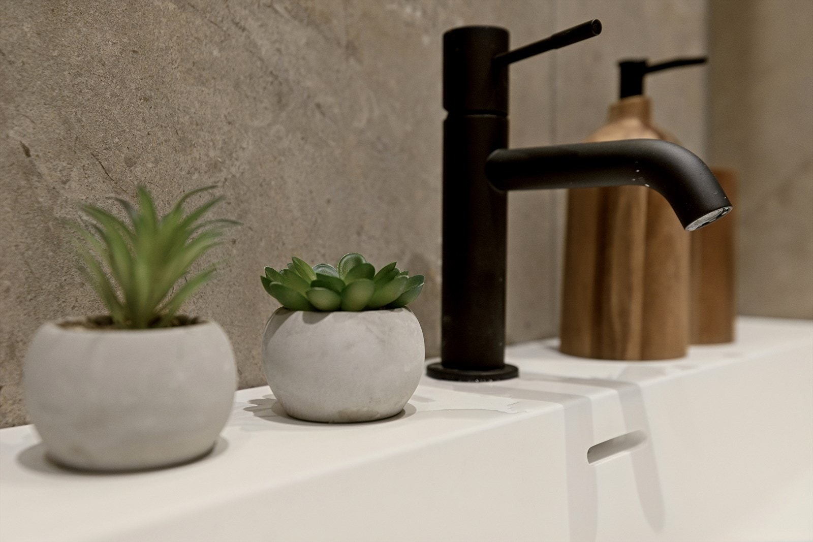 Baderomsinnredningen har en moderne servant med skuffer og en stilren, sort ettgrepskran. Galleribilde