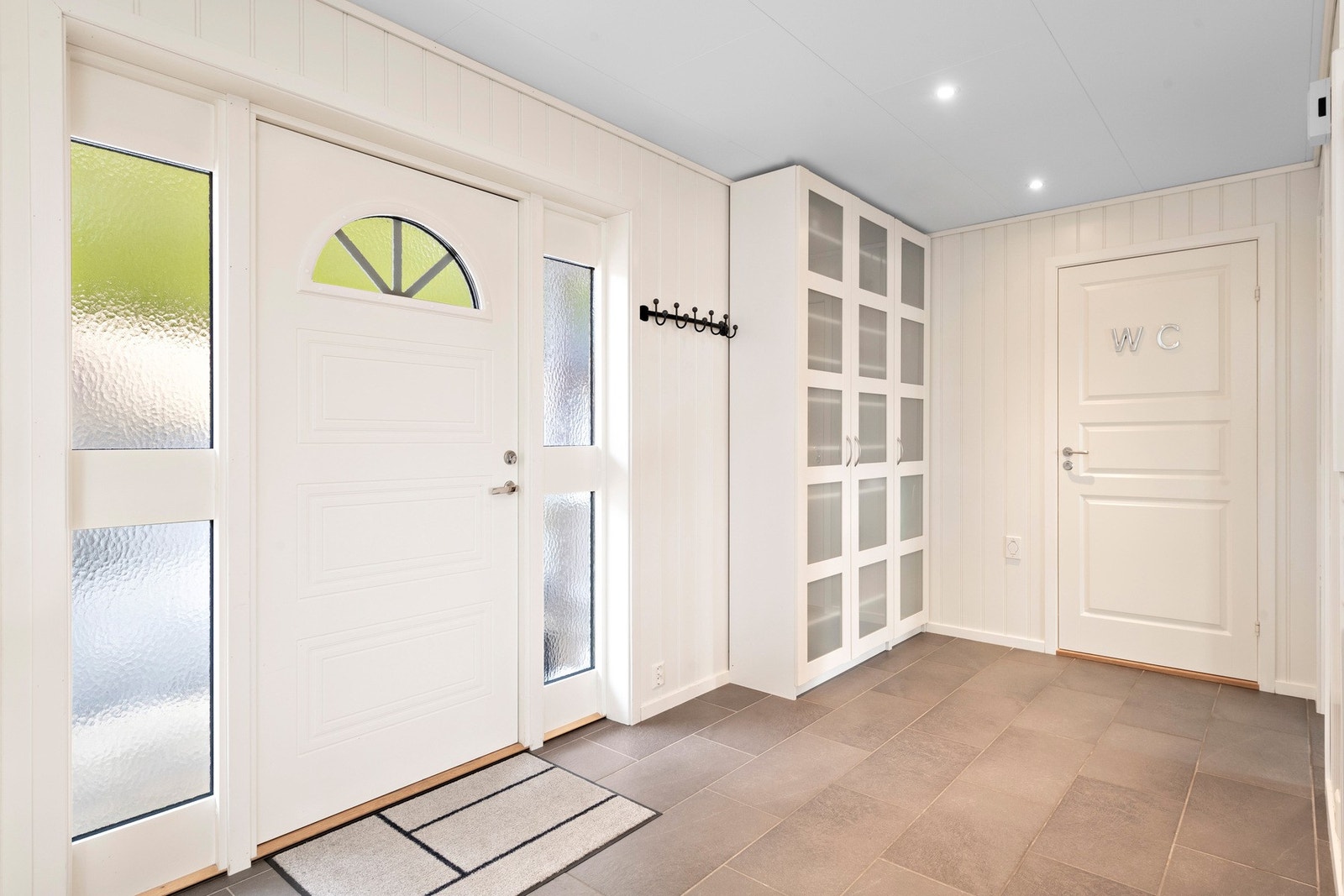 Det første som møter deg er en lys entré med fliser på gulv og downlights i himling. Galleribilde