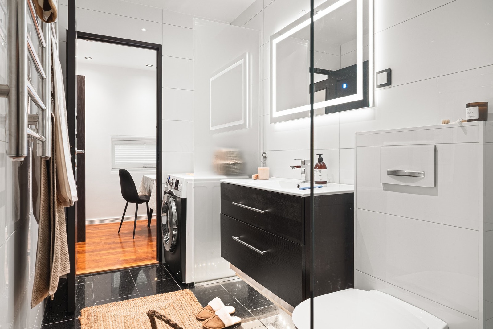 Badet har dusj med glassvegg, vegghengt toalett, baderomsinnredning og speil med lys. Galleribilde