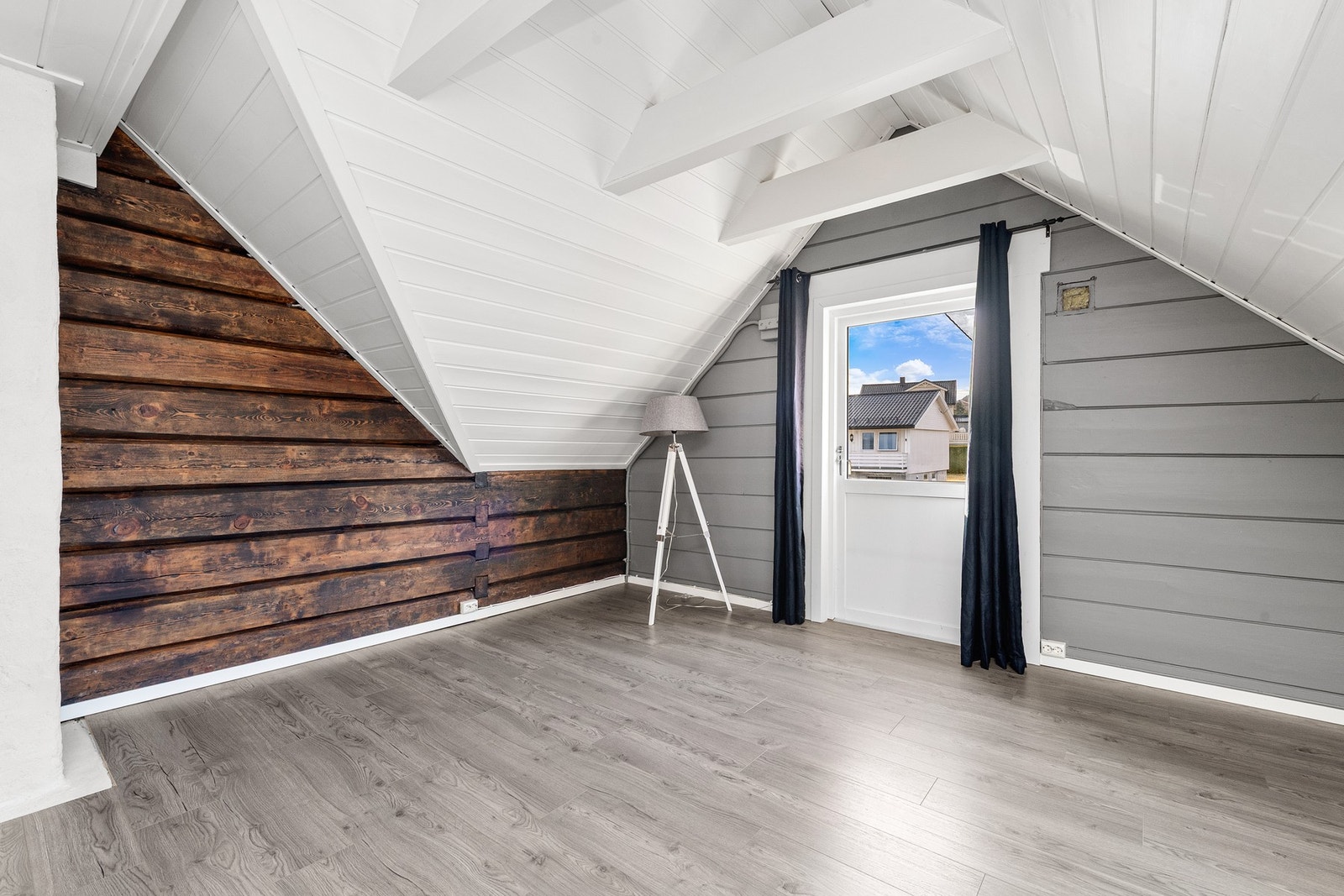 Loftsstue med pene detaljer av synlig tømmervegg. Stuen har adkomst til veranda. Galleribilde
