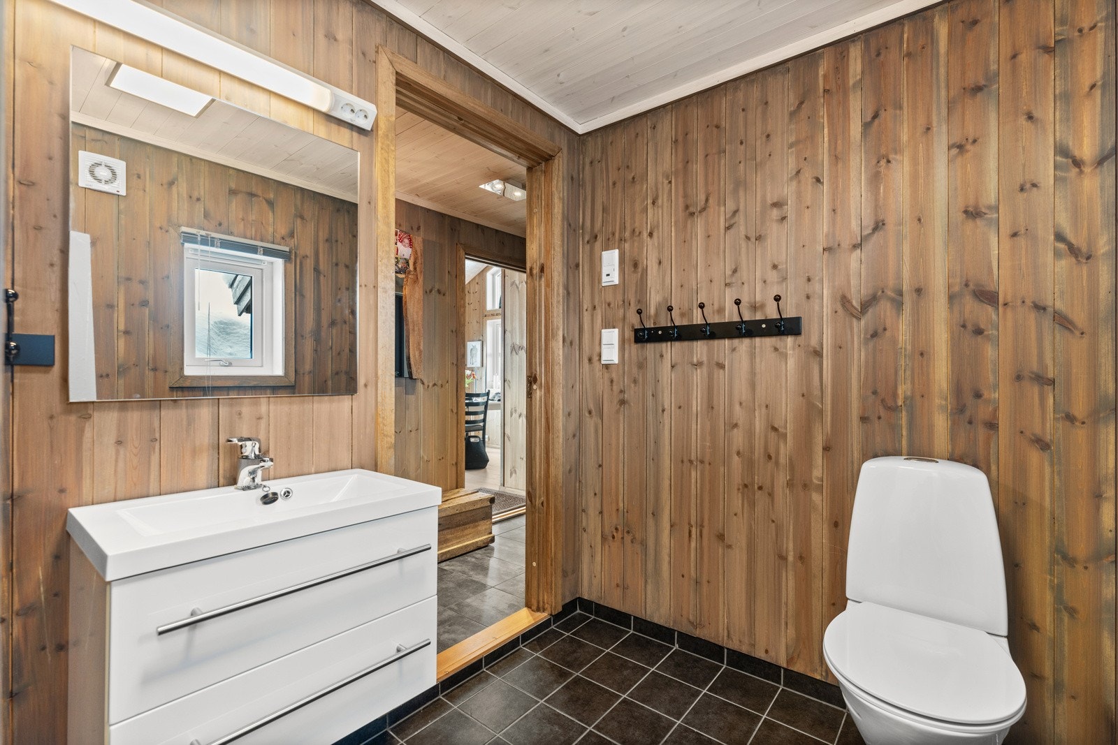 Bad I har fliser med varmekabler på gulv, panel på vegger og lys baderomsinnredning. Galleribilde