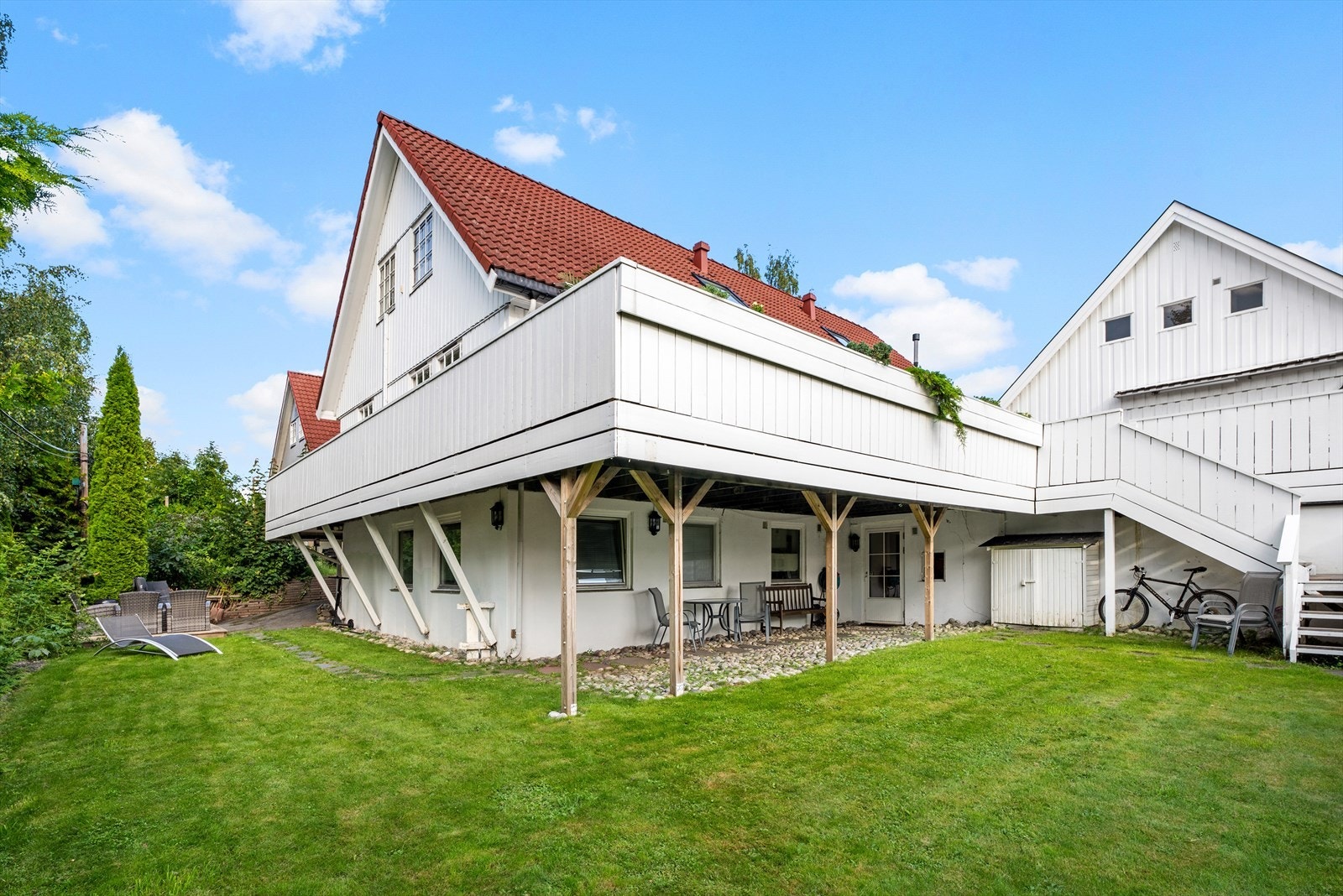 Stor, lettstelt hage på nedsiden av huset, redskapsbod og flere plasser for sittegrupper. Galleribilde