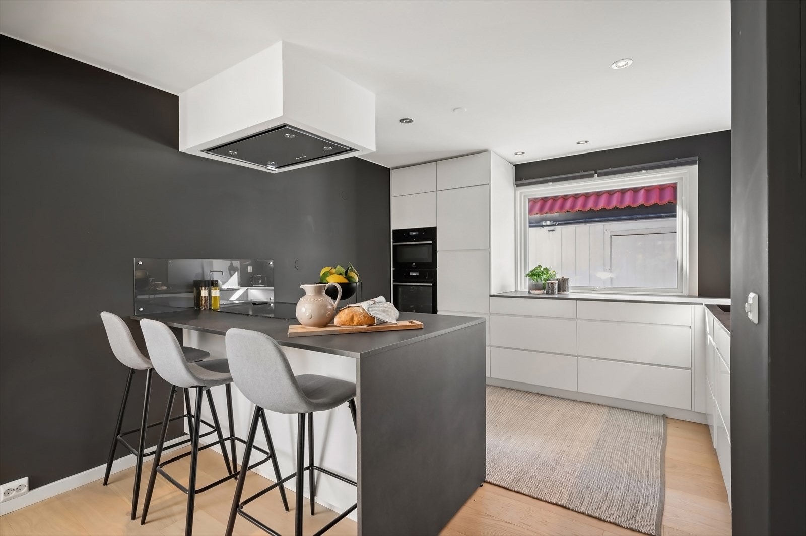 Stilrent kjøkken med halvøy med integrert platetopp samt sittegruppe. Galleribilde