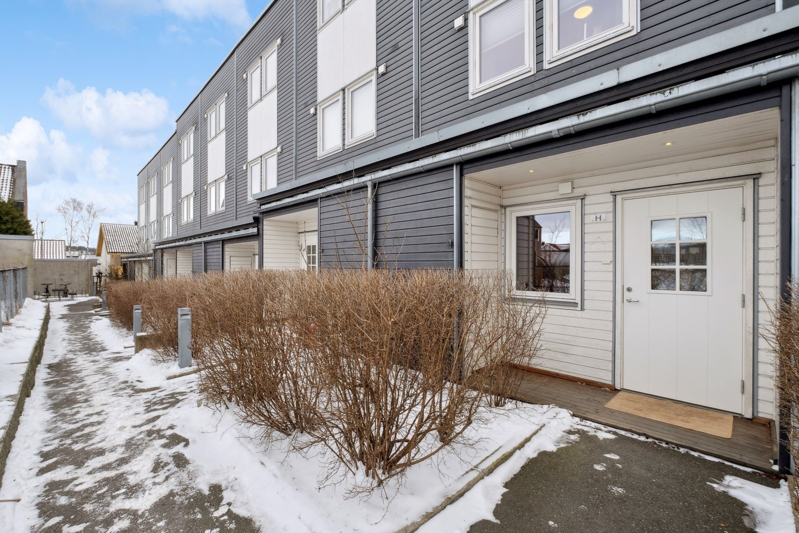 Det er en liten utebod ved det overbygde inngangspartiet. Det er i tillegg en sportsbod ved garasjen i nabobygget. Galleribilde