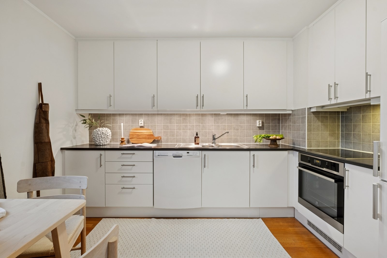 Kjøkkenet har godt med benk- og skapplass. Overskapene går helt opp i taket. Det er fliser mellom benk og overskap. Galleribilde