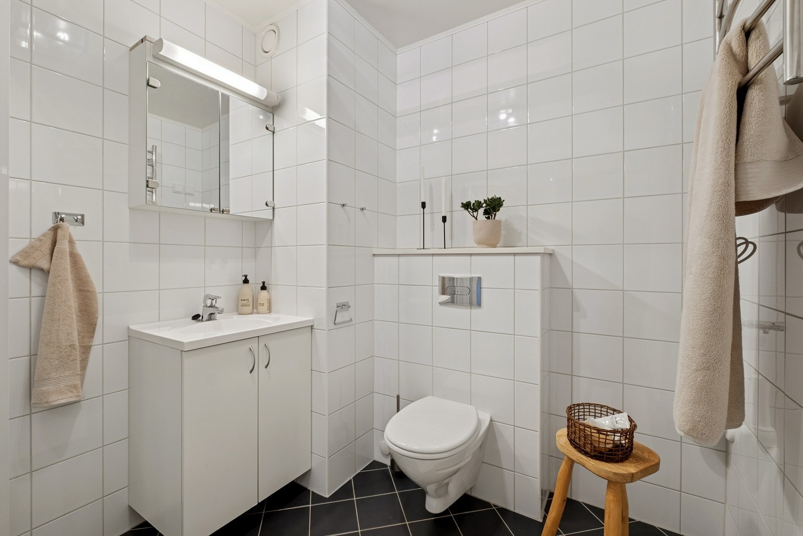 Det er tidløse hvite fliser på vegger og sorte fliser på gulvet. Vegghengt toalett. Galleribilde