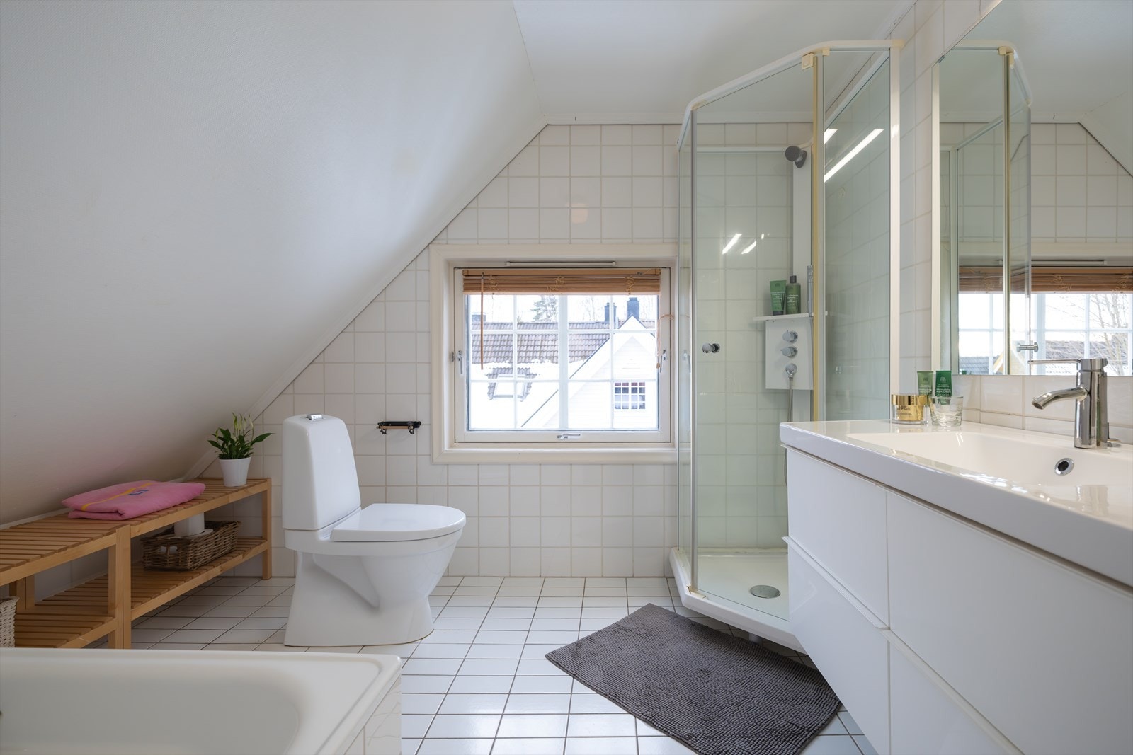 Flislagt bad med dusj i badekar, dusjkabinett, servant og klosett Galleribilde