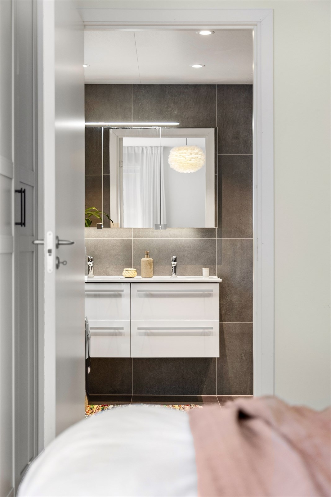 Badet er tilknyttet hovedsoverommet og har delikate, flislagte overflater. Galleribilde