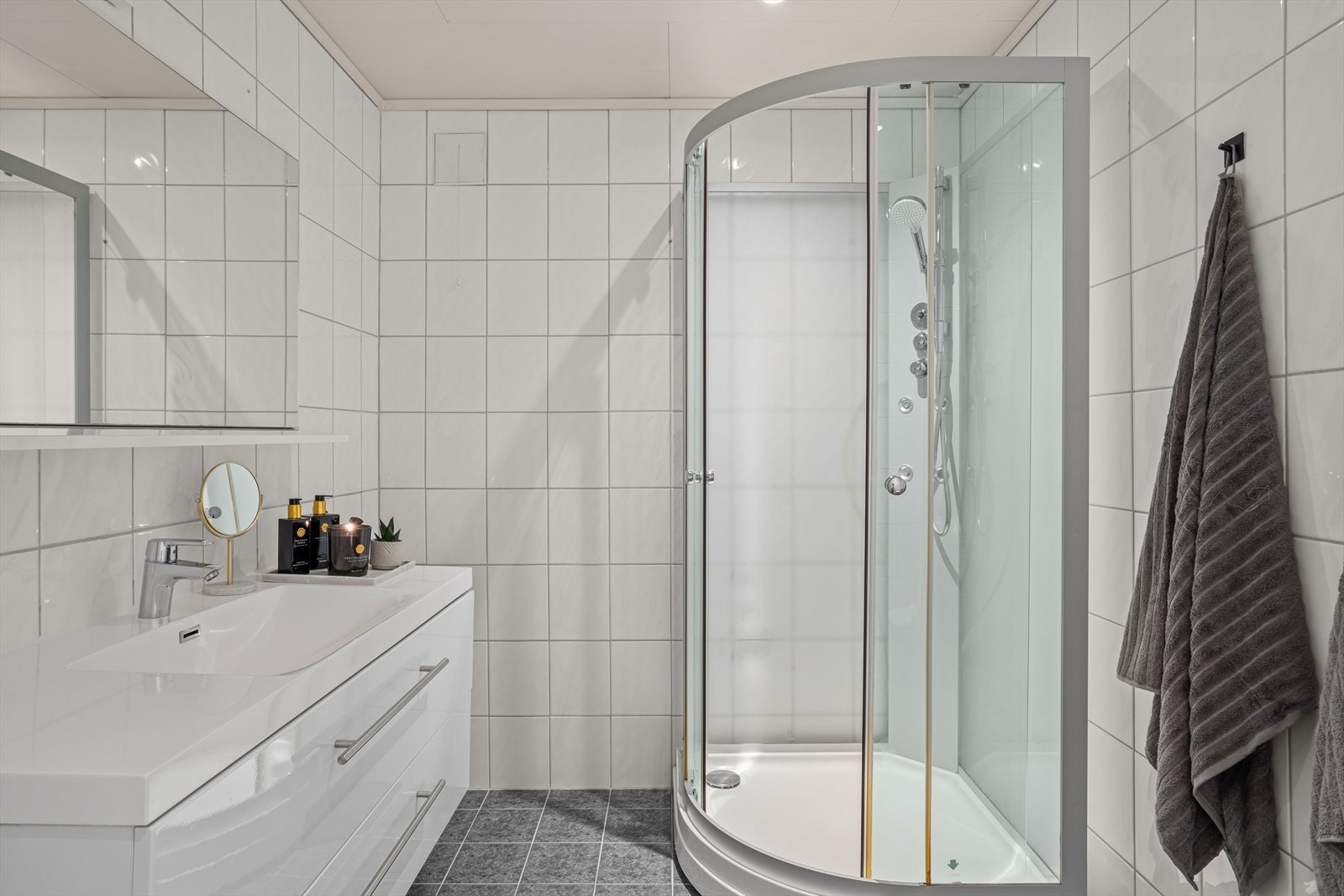 Flislagt baderom i sokkel er flislagt og utstyrt med dusjkabinett og servantinnredning. Galleribilde