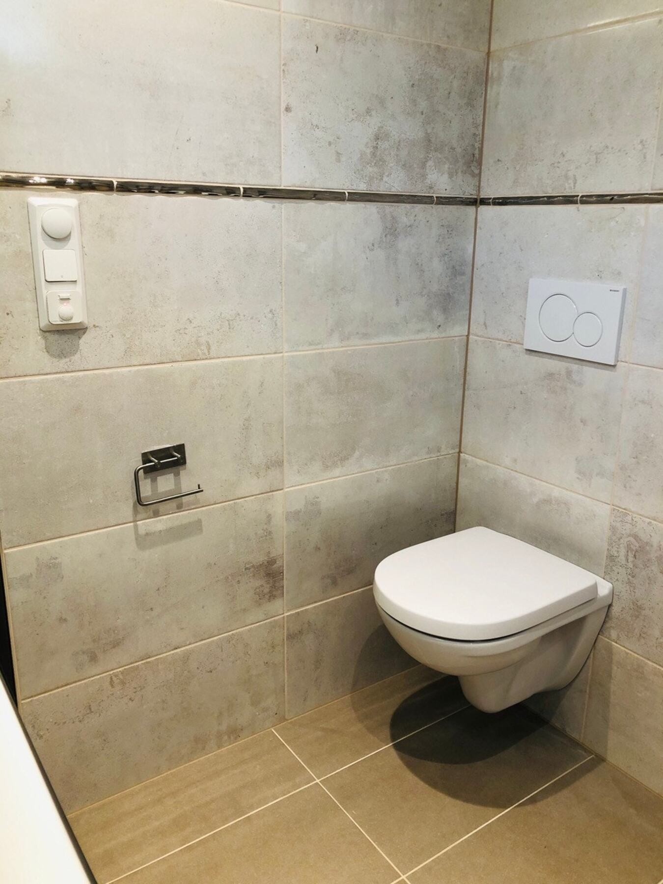 Badet er rehabilitert i perioden 2019-2022 med flislagte overflater, vegghengt toalett, servant med baderomsinnredning og dusj på gulv. Galleribilde