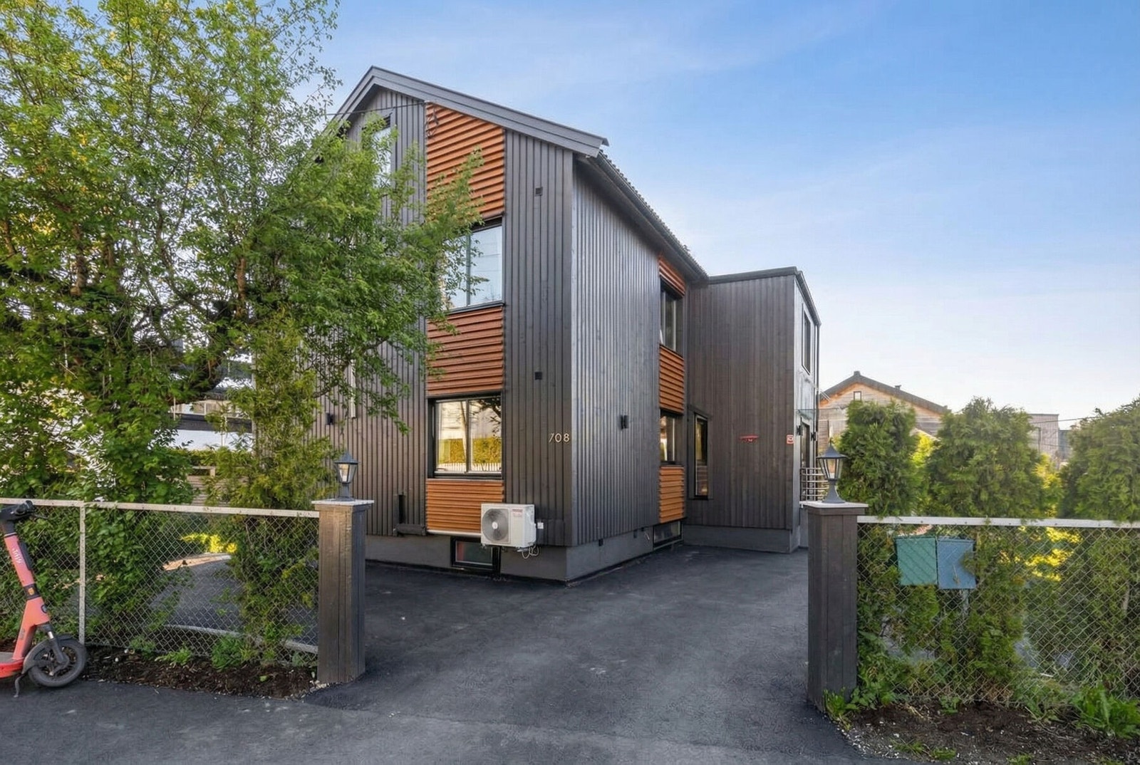 Det er rikelig med parkering på egen tomt. På gårdsplassen er det montert elbillader. Bildet er KI-generert for å illustrere sommerforhold. Galleribilde