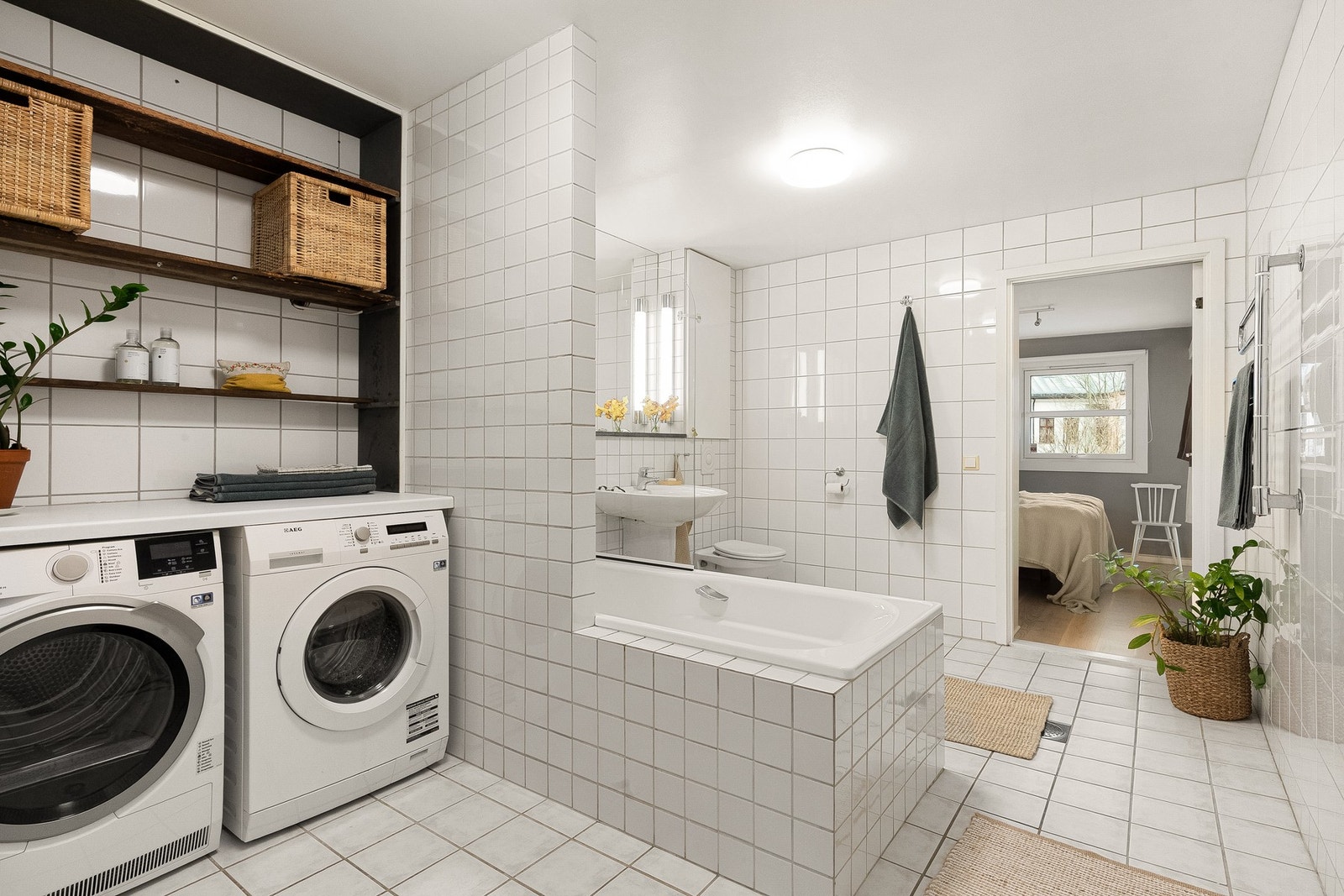 Tidløst flislagt baderom med termostatstyrte varmekabler i gulv, samt opplegg for vaskemaskin og tørketrommel. Galleribilde