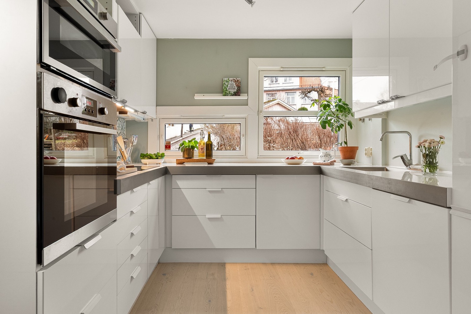 Kjøkkeninnredningen har takhøy hvite, glatte fronter og laminatbenkeplate med nedfelt kum i rustfritt stål. Galleribilde