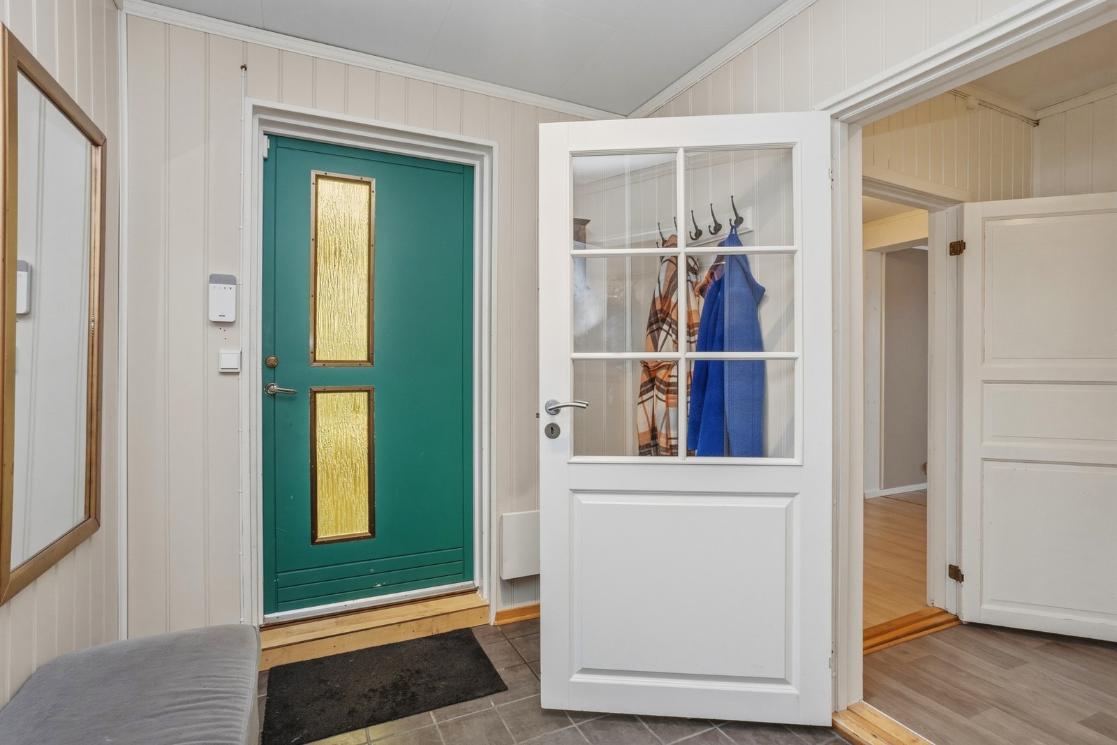 Romslig entré med flislagt gulv, panelplater på vegger og takplater i himling Galleribilde