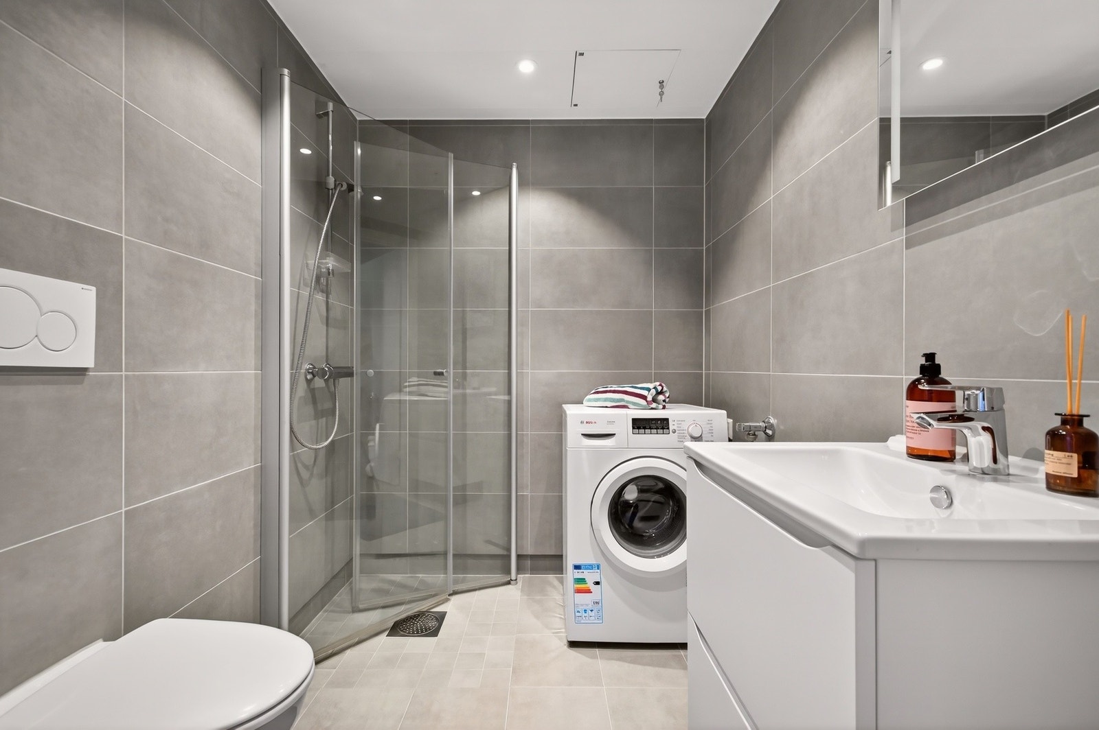 Pent, flislagt bad med opplegg for vaskemaskin. Tidsriktig baderomsinnredning Galleribilde