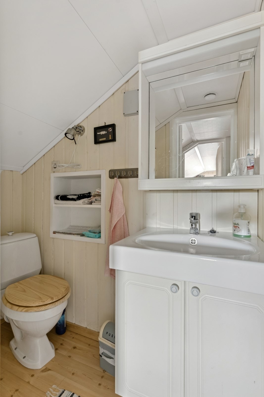 Toalettrom i loftetasje med golvståande toalett og skapinnreiing med servant. Galleribilde