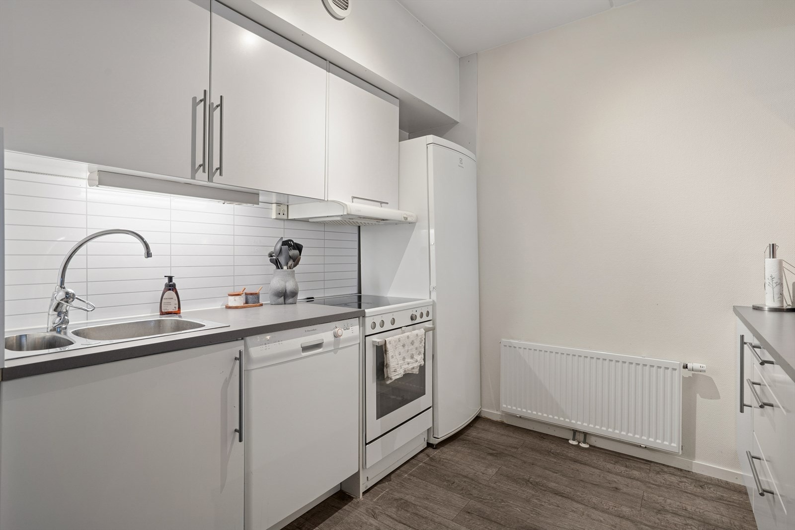 Kjøkkeninnredningen har glatte fronter og praktiske, vannbestandige plater over benken. Galleribilde