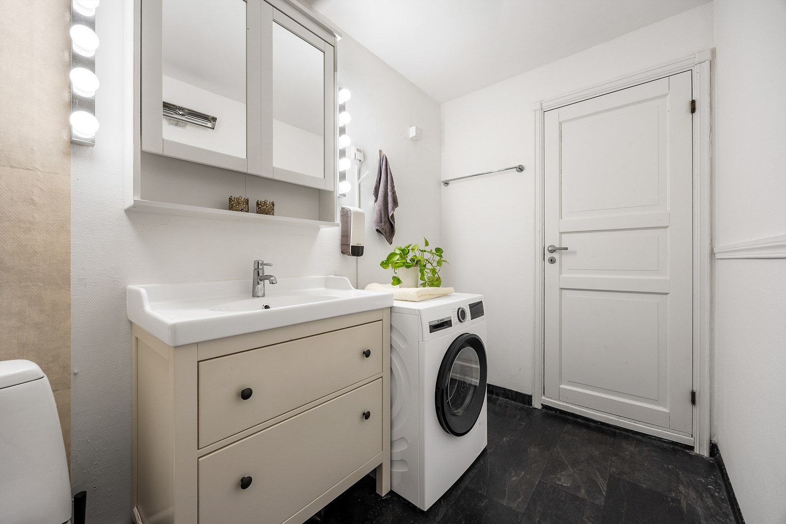 Badet er utstyrt med servantinnredning, speilskap, gulvstående toalett og opplegg for vaskemaskin. Galleribilde