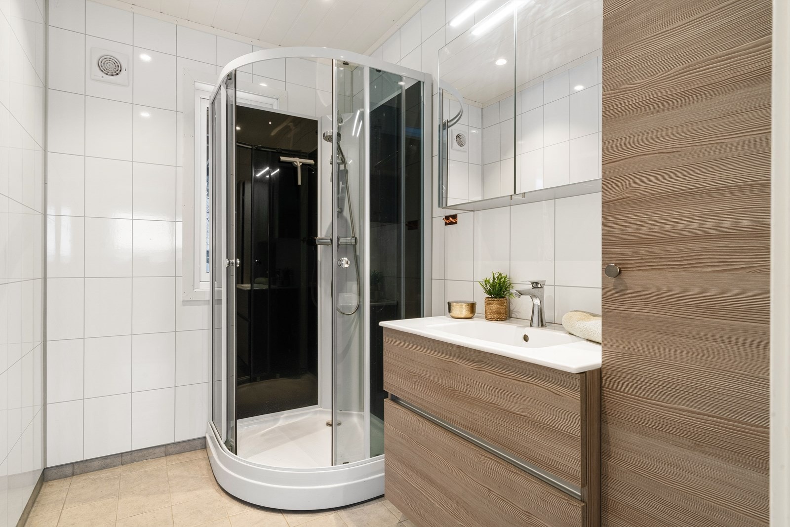 Bad med dusjkabinett, servant med skuffer, skap med speil og vegghengt oppbevaringsskap. Galleribilde