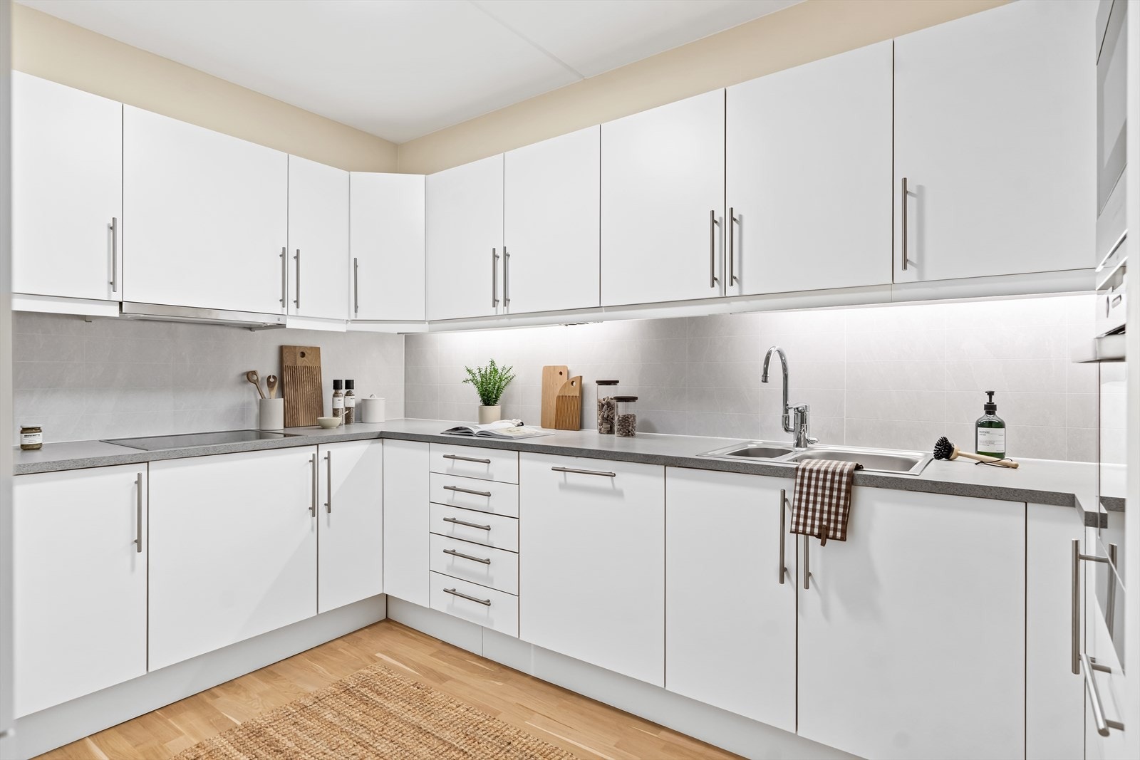 Innredningen har skap med hvite slette fronter, samt grå benkeplate i laminat med nedfelt og overlimt 1,5 vaskekum i børstet stål. Galleribilde