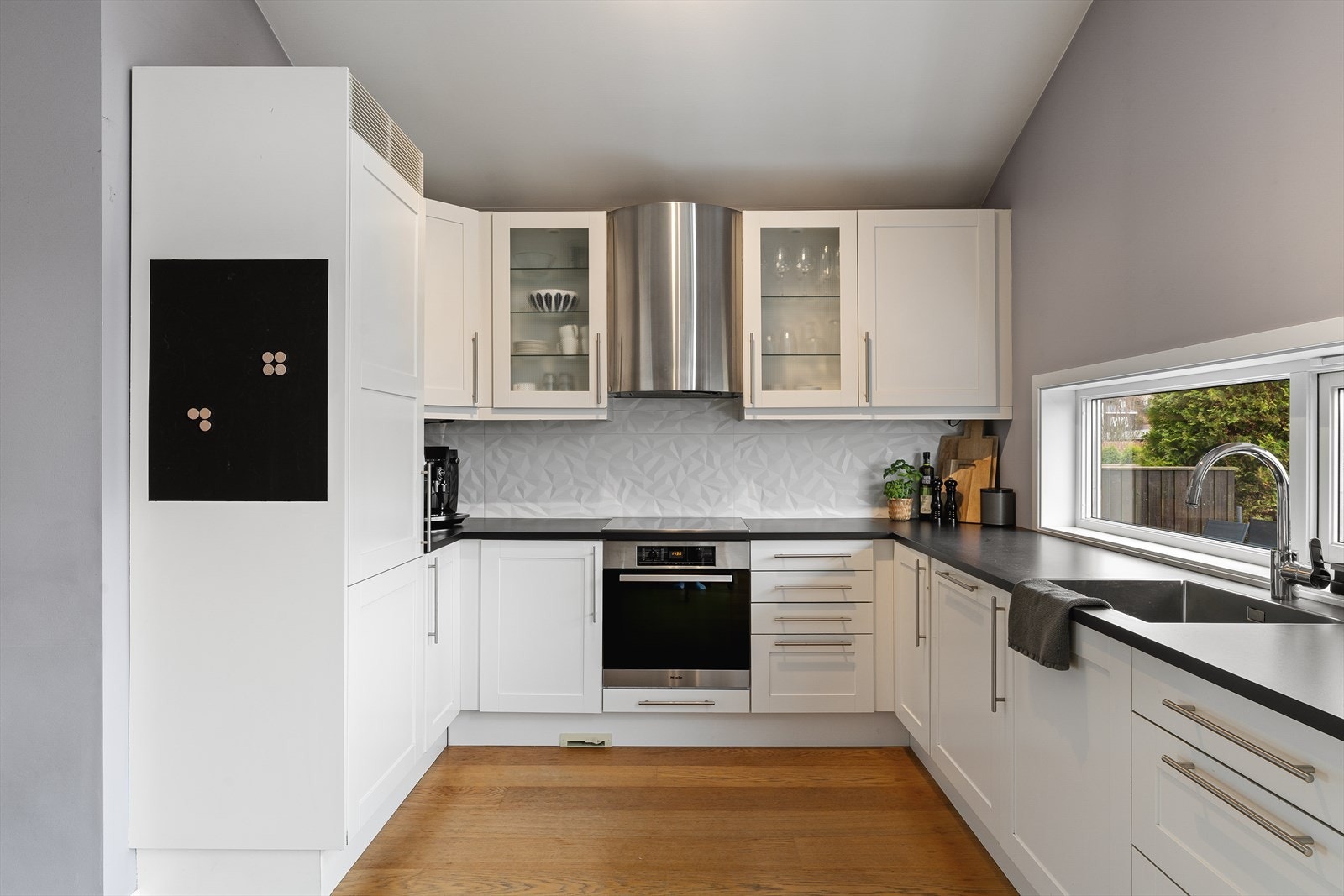 Innholdsrikt kjøkken med hvite profilerte fronter. Integrerte hvitevarer. Galleribilde