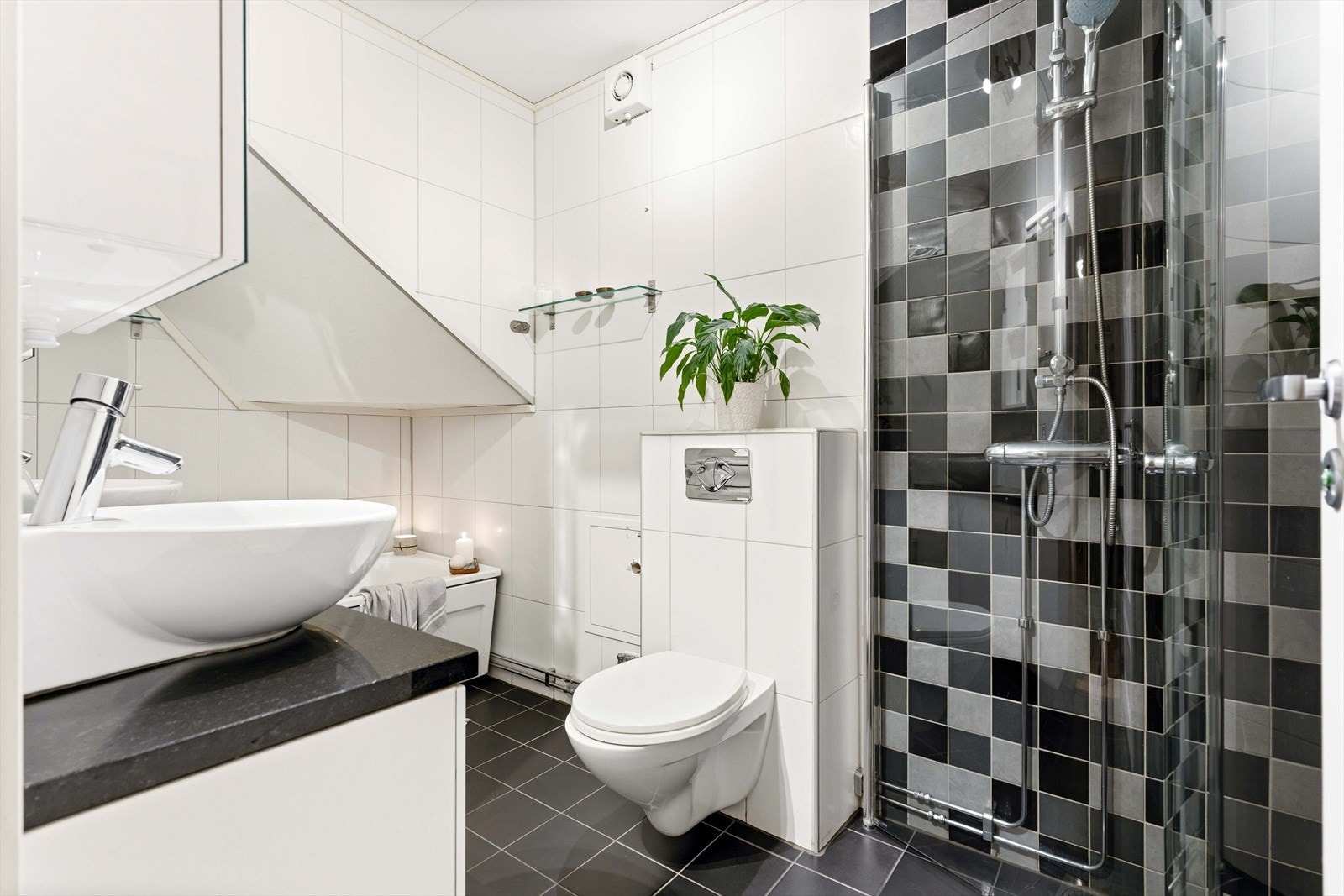 Badet i første etasje er helfliset og utstyrt med vegghengt toalett og et dusjhjørne med regnfallsdusj. Galleribilde