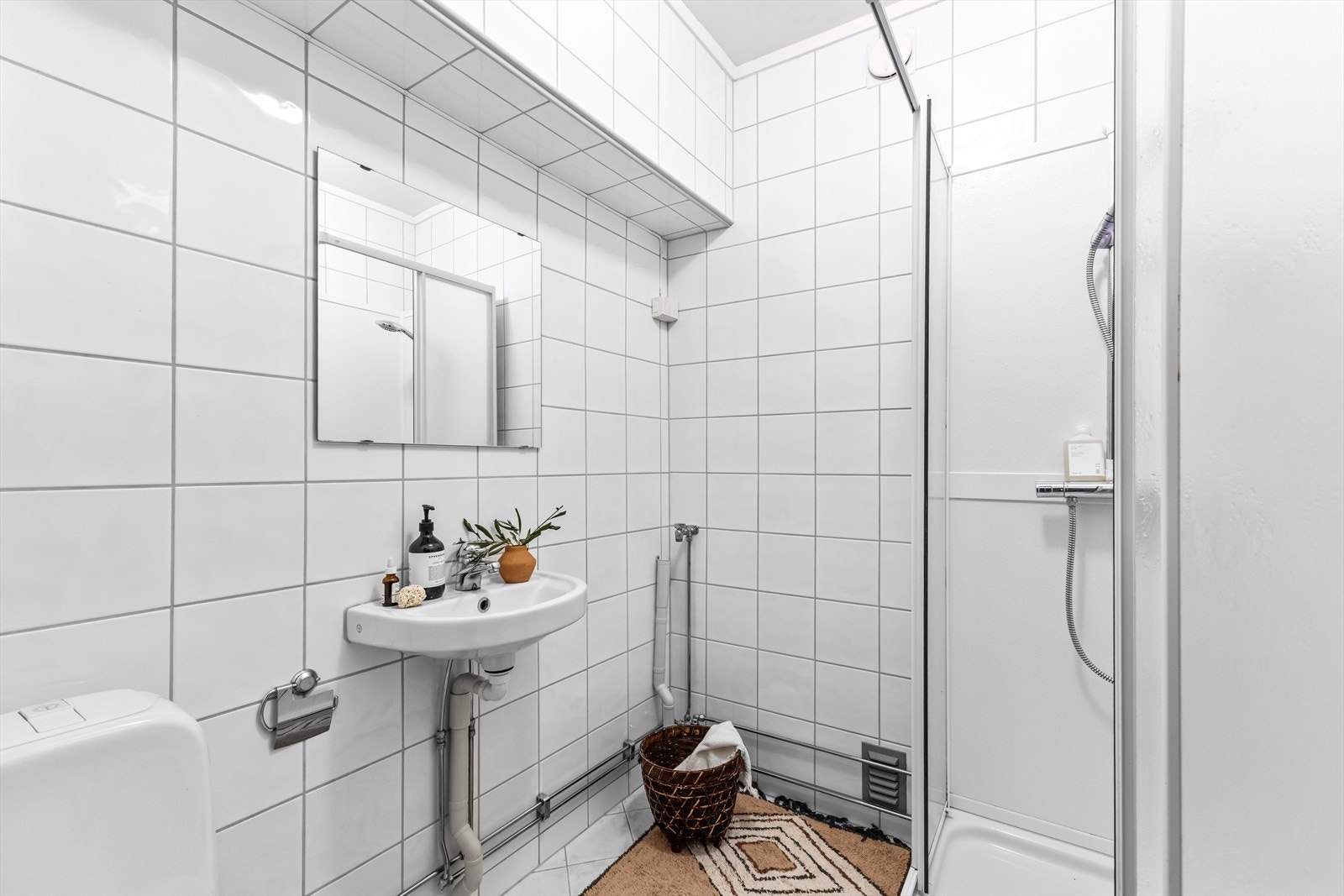 Badet er innredet med frittstående toalett, dusjkabinett og servant med blandebatteri. Det er opplegg for vaskemaskin. Galleribilde