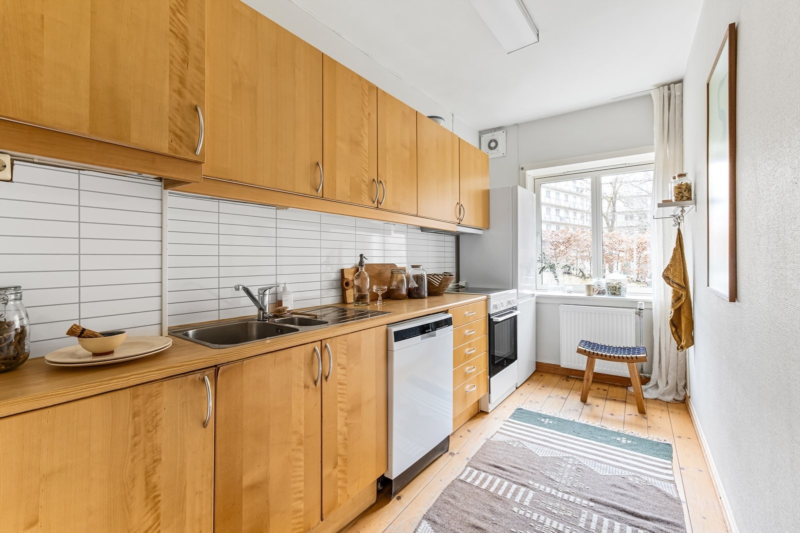 Separat kjøkken med slette fronter og fliser over laminat benkeplate. Galleribilde