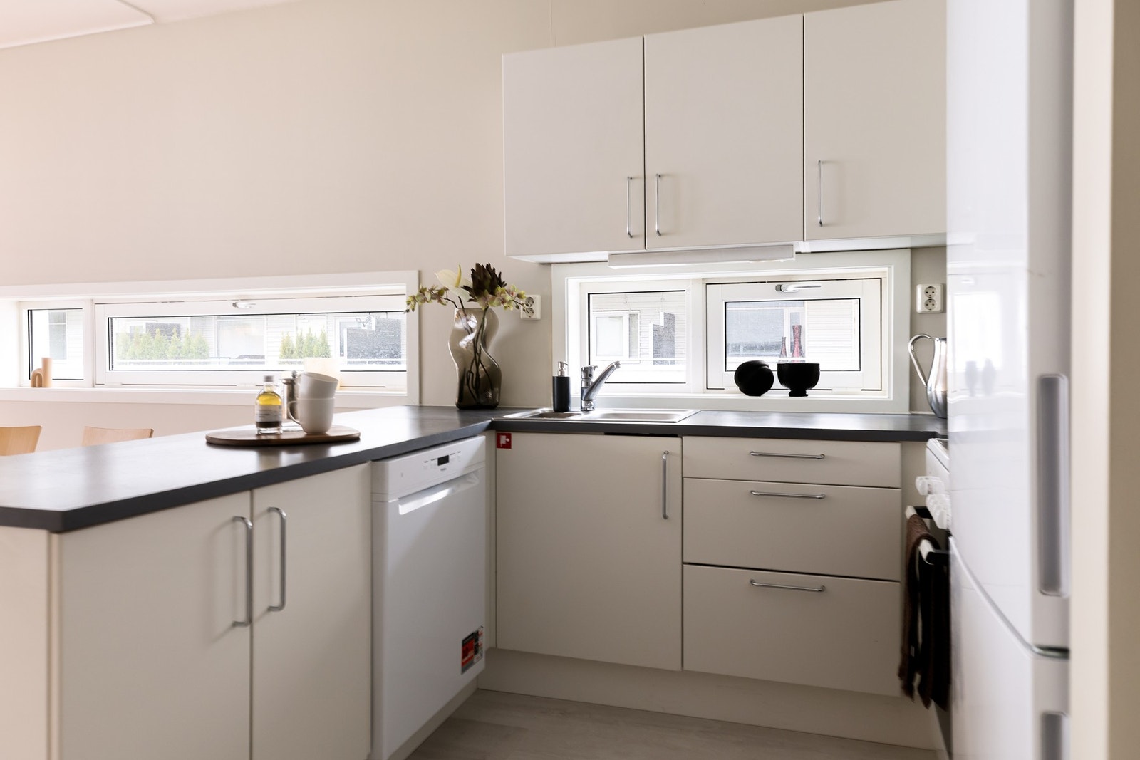 Lyst og tidsnøytralt kjøkken fra byggeår, med ny oppvaskmaskin fra 2026. Galleribilde