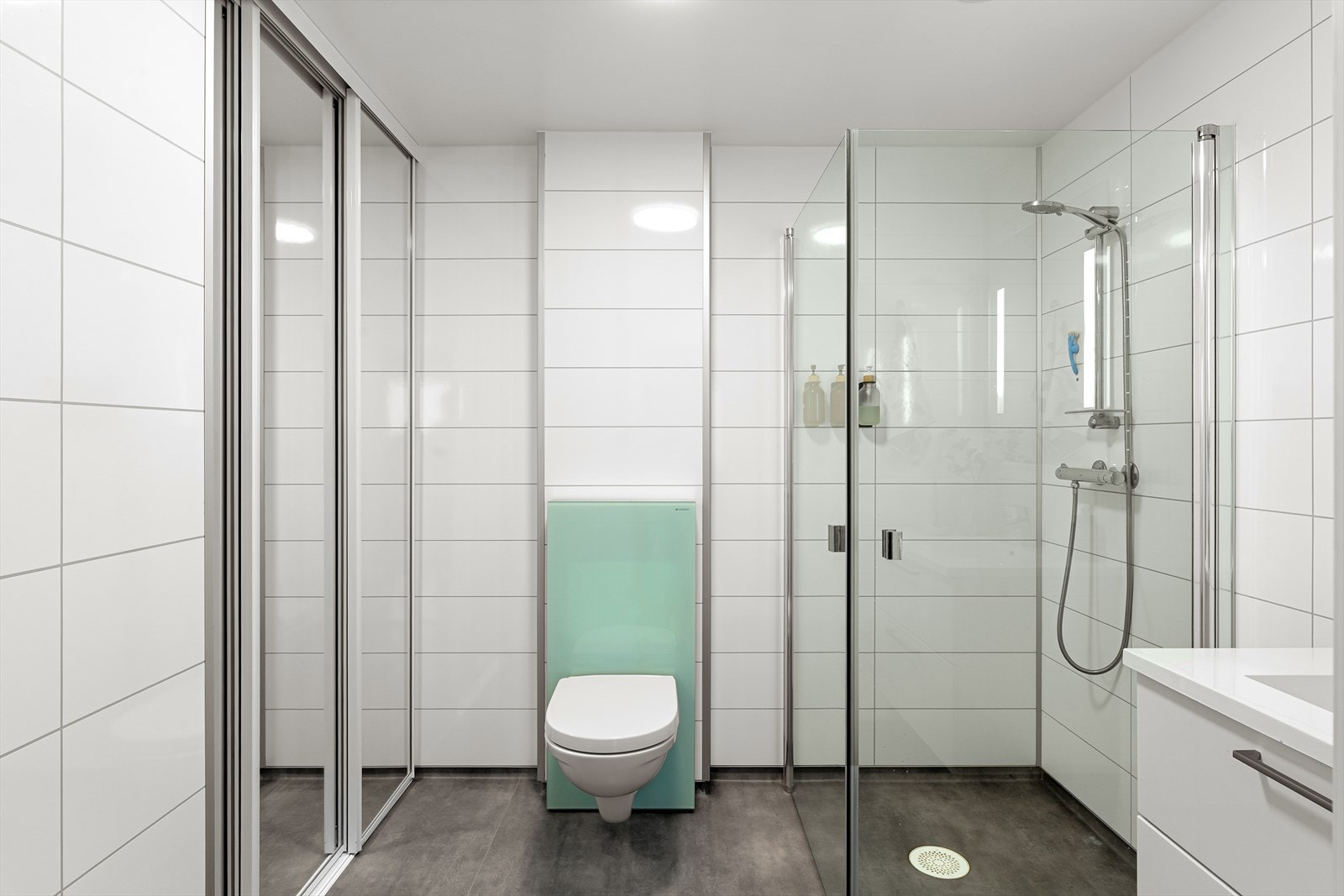 Dusjhjørne med innfellbare dusjdører og vegghengt toalett. Galleribilde