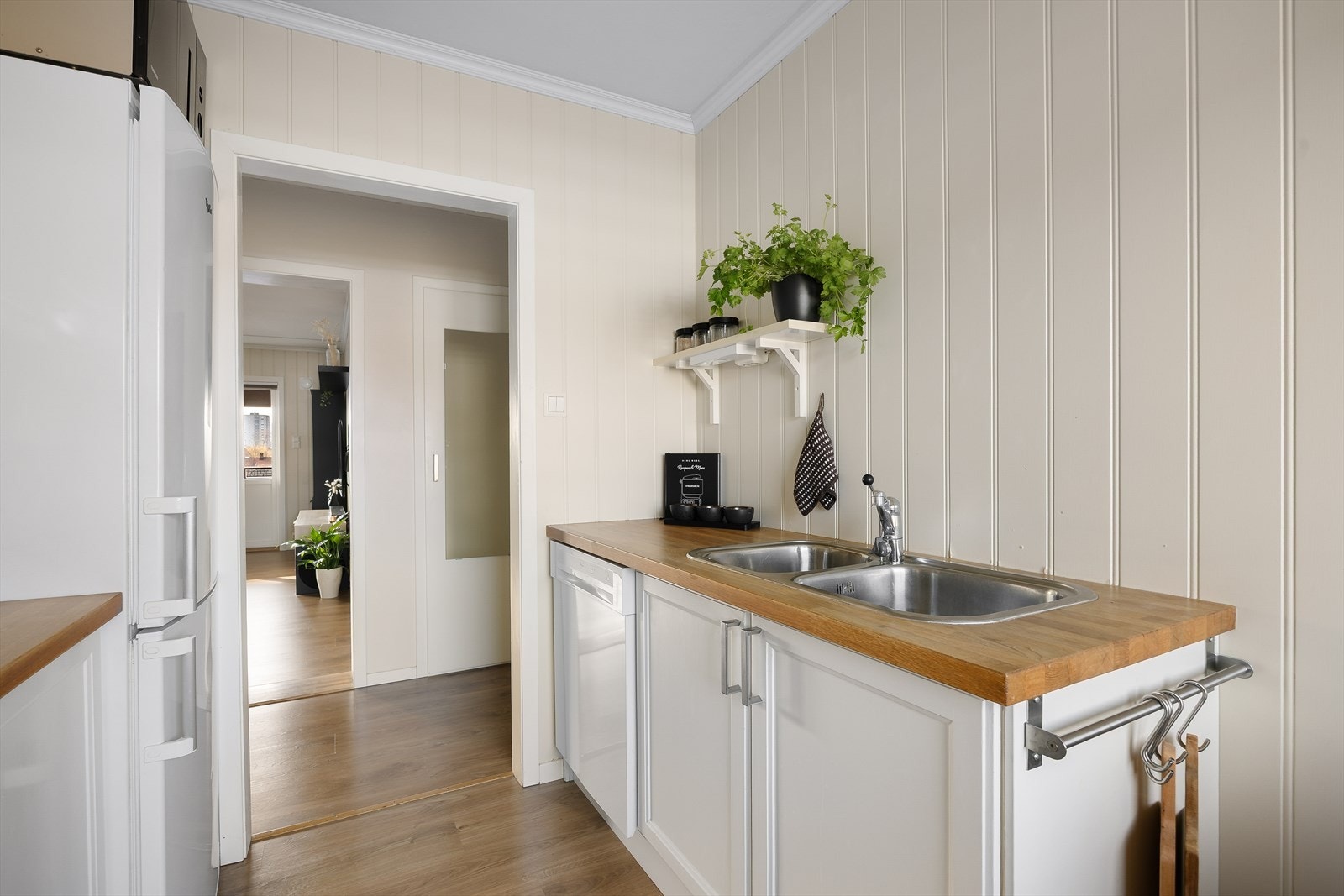 Lyst og koselig kjøkken med med profilerte fronter. Heltre benkeplate og nedfelt dobbel stålkum med et-greps blandebatteri Galleribilde