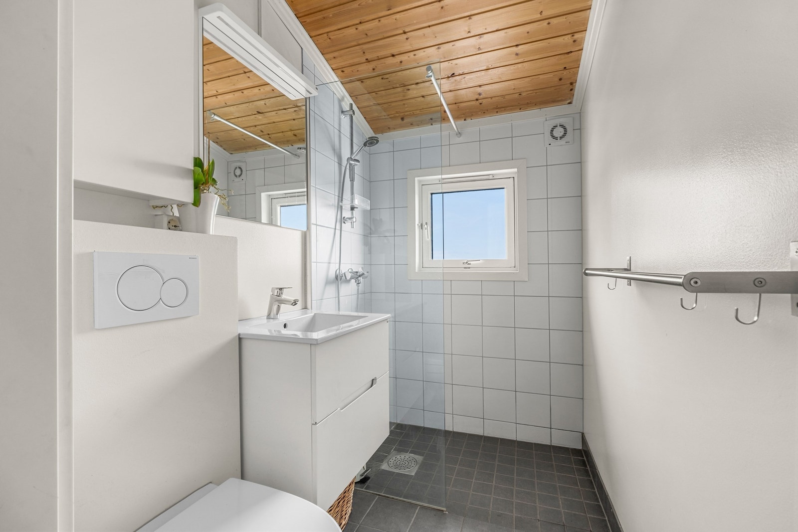 Pent delvis flislagt bad med gulvvarme, servantskap med speil og lys, vegghengt toalett og dusjhjørne. Galleribilde