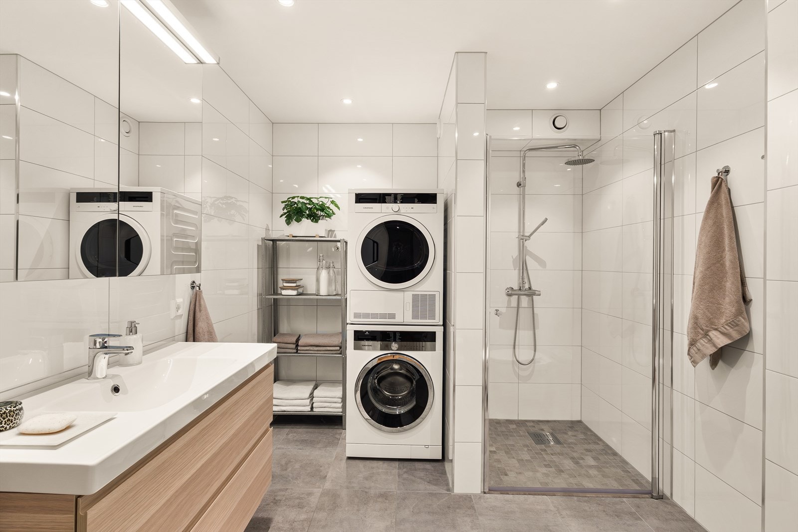 Badet fremstår delikat og moderne med vegghengt toalett, dusjnisje og servant med underskap. Galleribilde