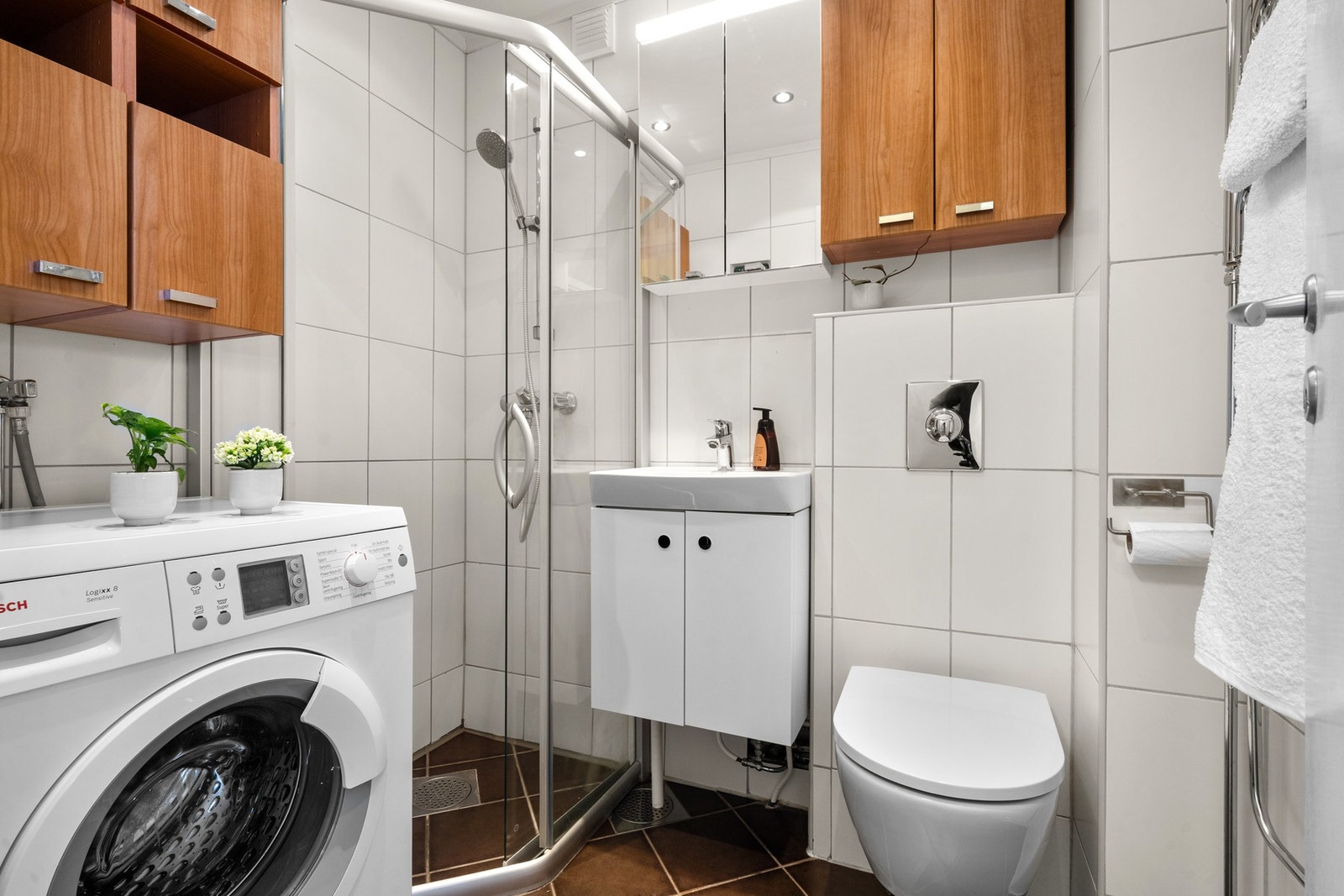 Flislagt baderom med termostatstyrte varmekabler, opplyst å være fra 2006. Ny fuge lagt i 2026. Rommet har dusjhjørne, servant med underskap, speil med belysning og opplegg for vaskemaskin. Galleribilde