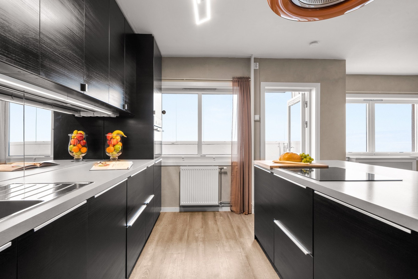 Kjøkkenøyen skaper en naturlig romfordeling mellom kjøkken og stue, og gir ekstra arbeidsflate samt en hyggelig sosial sone. Galleribilde