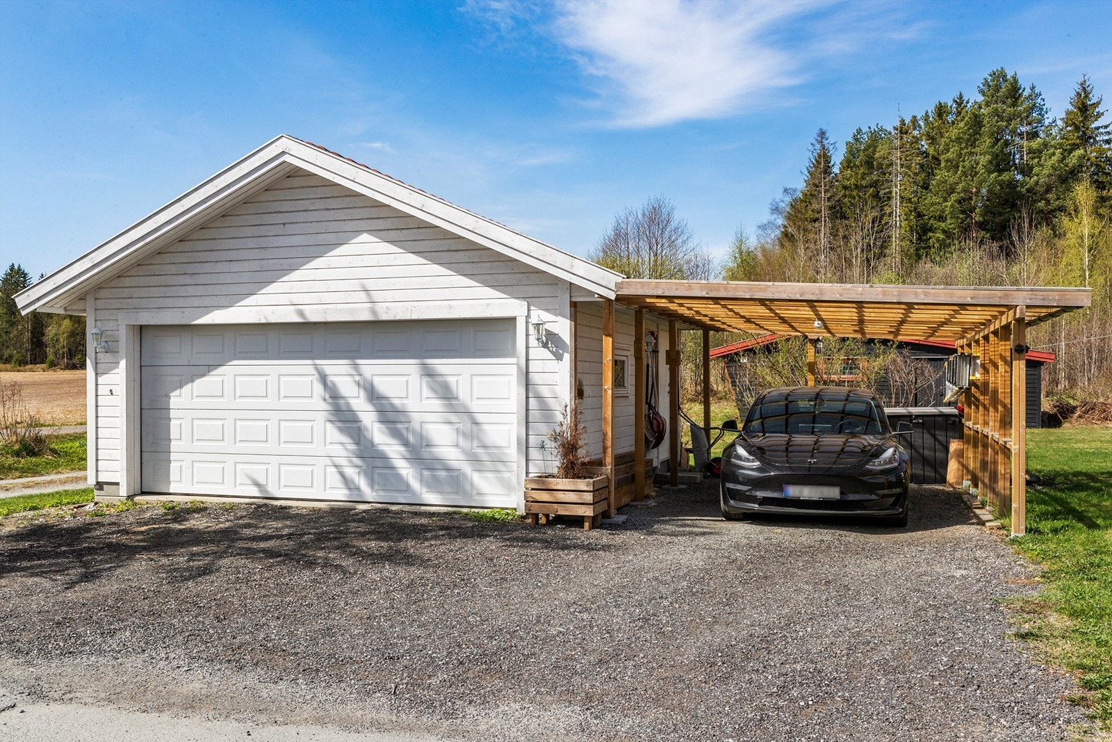 Parkering i dobbel garasje og i carport. Det er også plass til flere biler på gårdsplass. Elbillader ble montert i 2023. Galleribilde