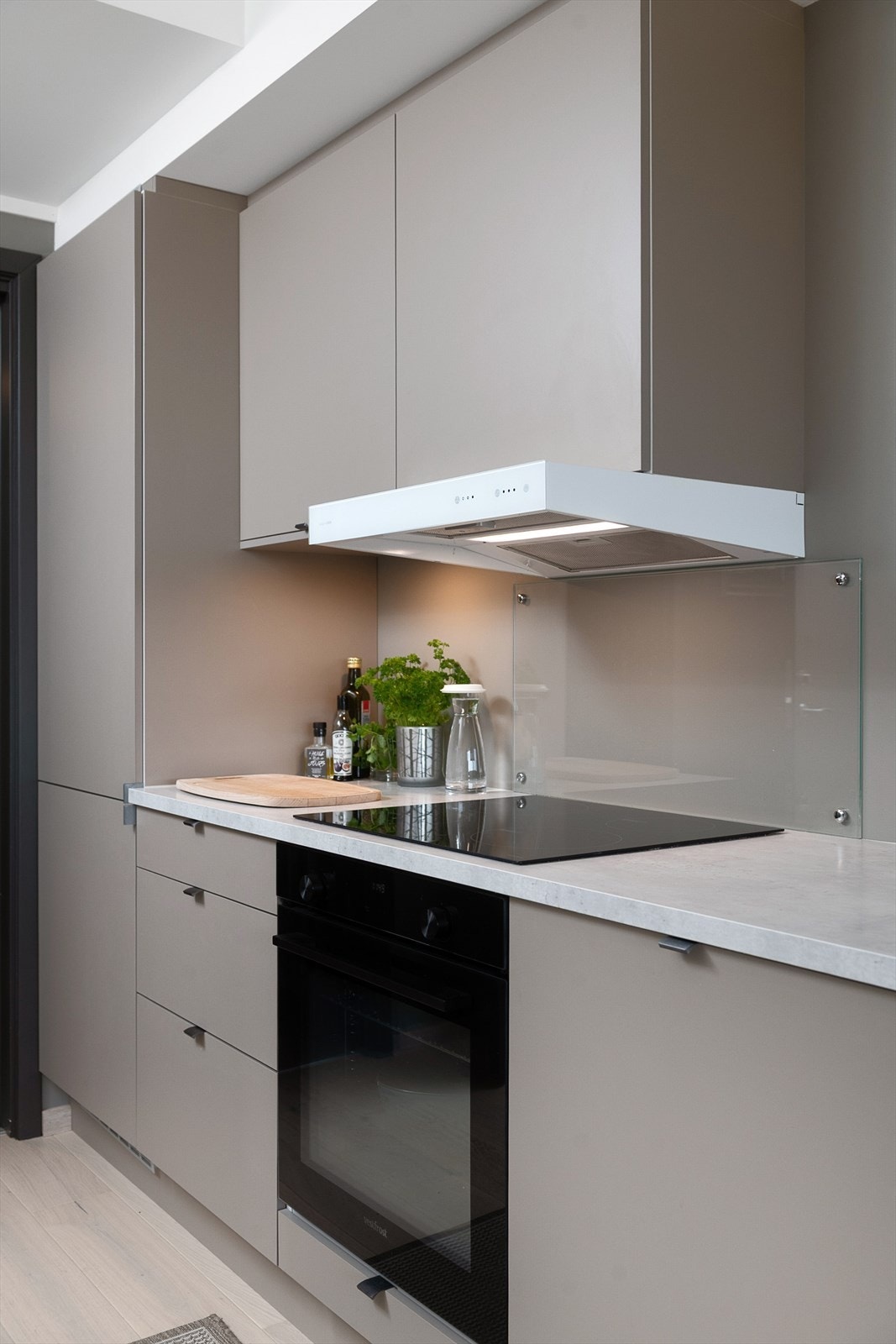 Kjøkkenet inneholder komfyr, oppvaskmaskin og kjøleskap. Glassplate over komfyr. Galleribilde