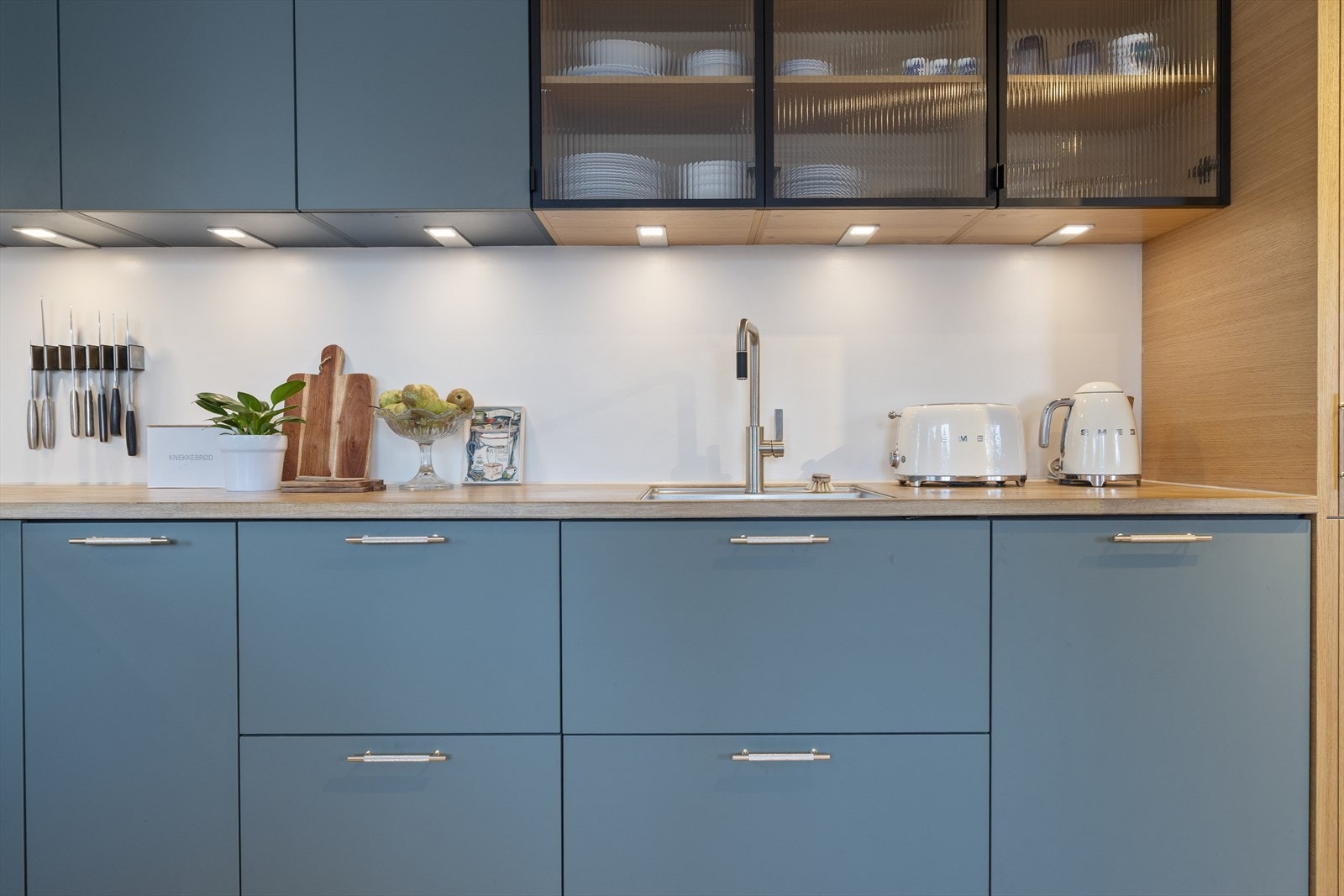 Kjøkkenet ble renovert i 2024 og har glatte fronter med håndtak og heltre benkeplater. Det er nedfelt stålkum med blandebatteri, integrert koketopp, oppvaskmaskin, stekeovner og kombinert kjøl/frys. Alle hvitevarer fra Siemens og Electrolux Galleribilde